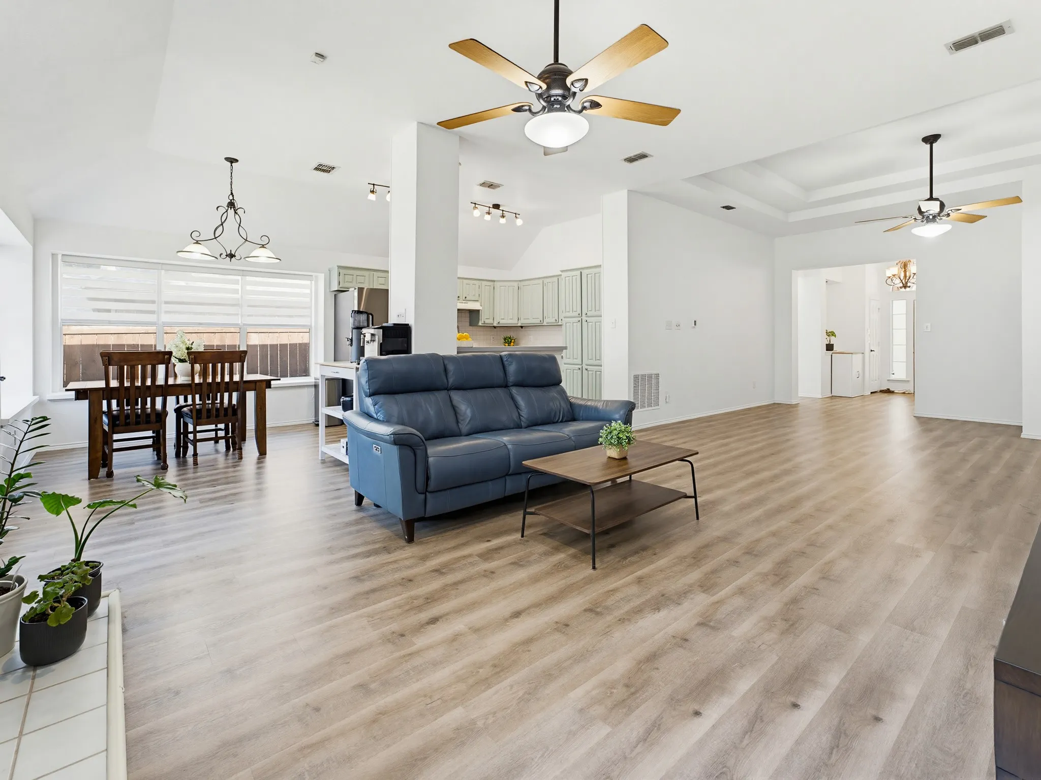 Expansive living area featuring wood-finish flooring, vaulted ceilings, and a tray ceiling