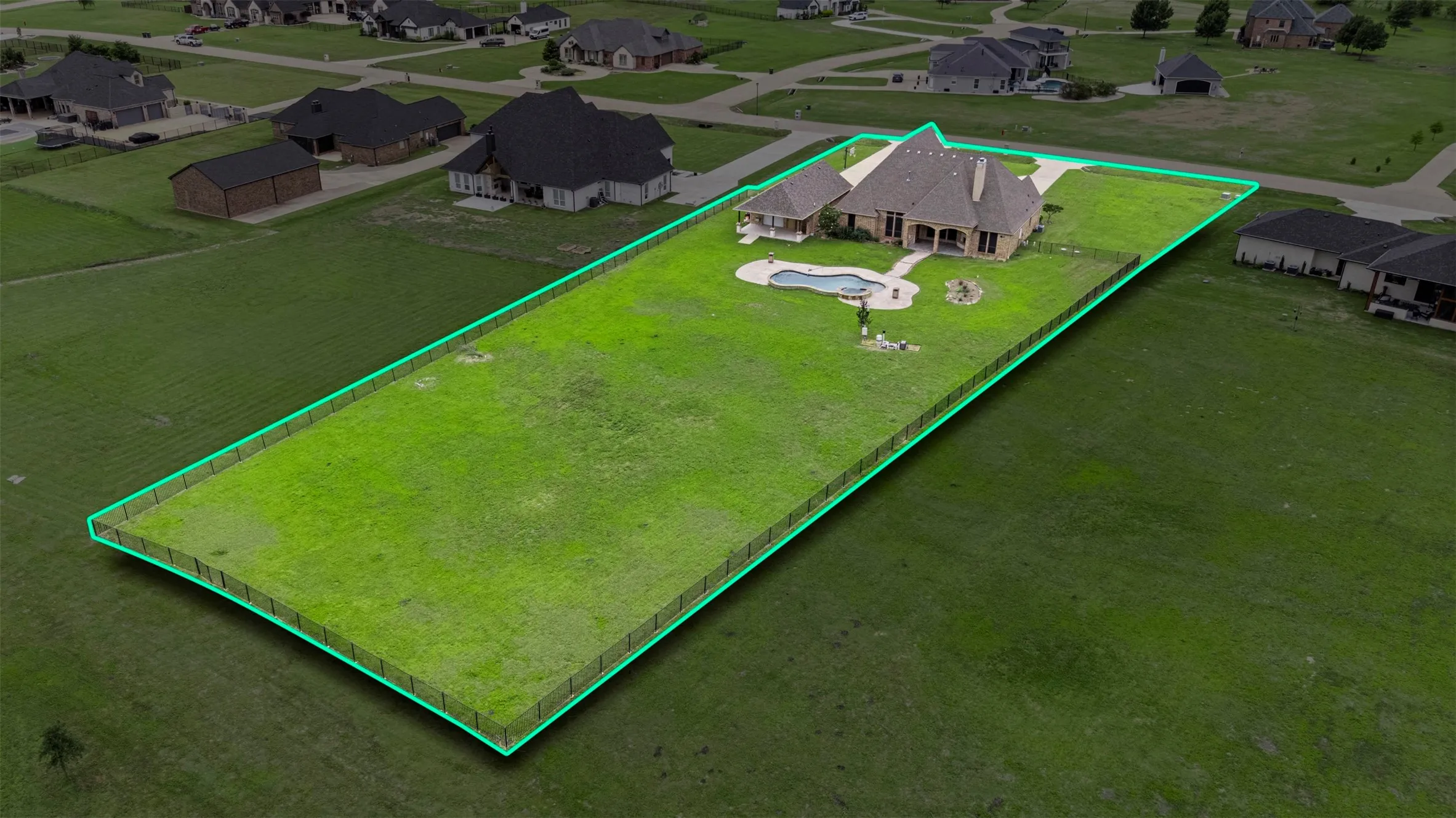 Spacious property featuring a brick exterior home with a gabled roofline, a fenced backyard, and a swimming pool with a surrounding concrete patio