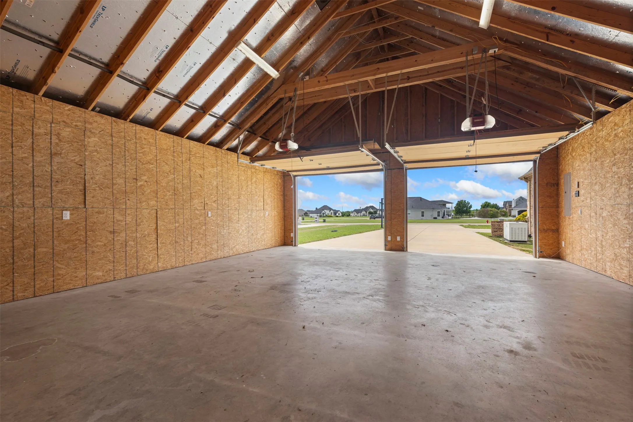 Second Garage.  vaulted ceiling, concrete flooring, two automatic garage door openers, and oriented strand board walls
