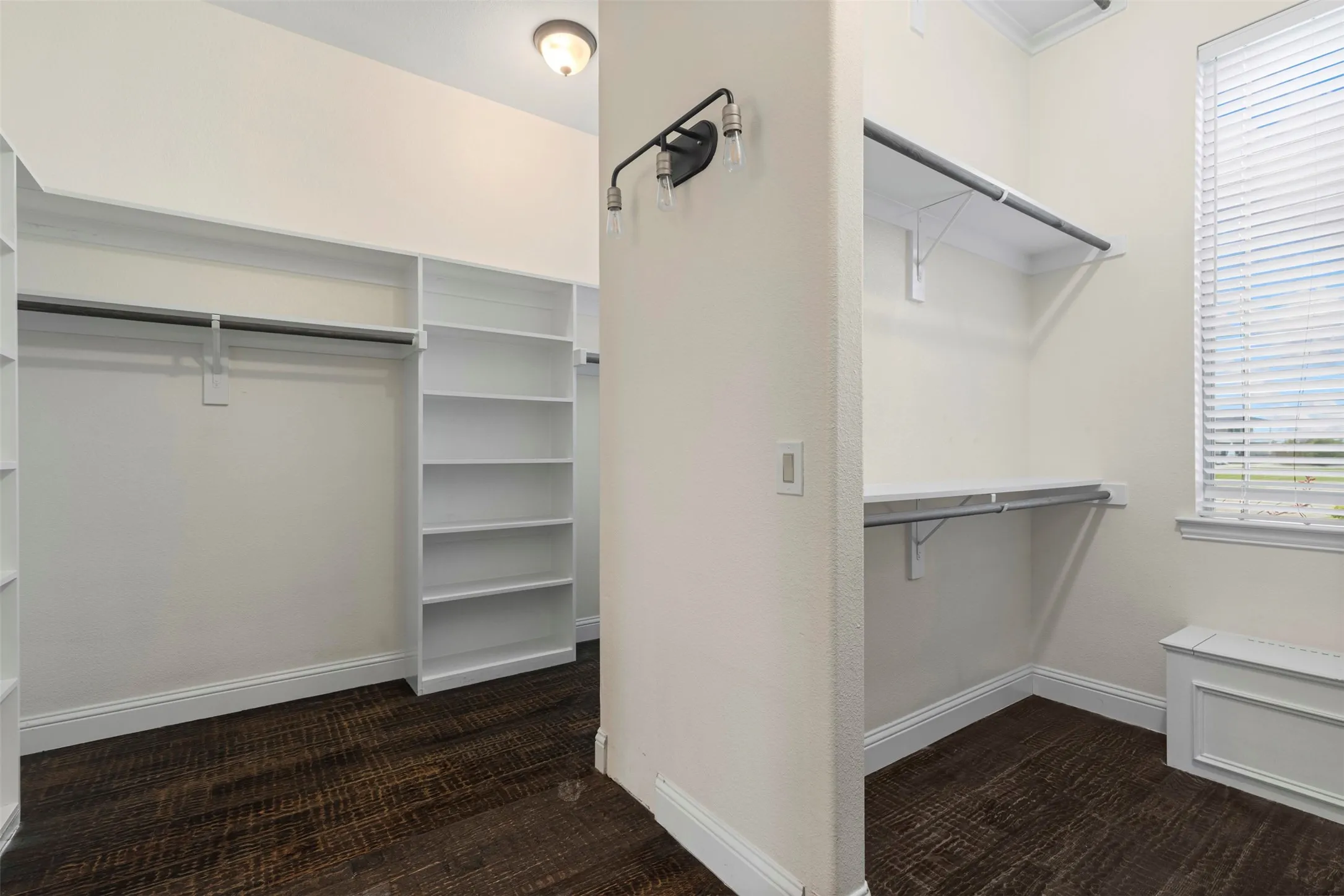 Walk-in closet featuring wood-finish flooring, built-in shelving, hanging rods, an integrated window, and a built-in storage bench