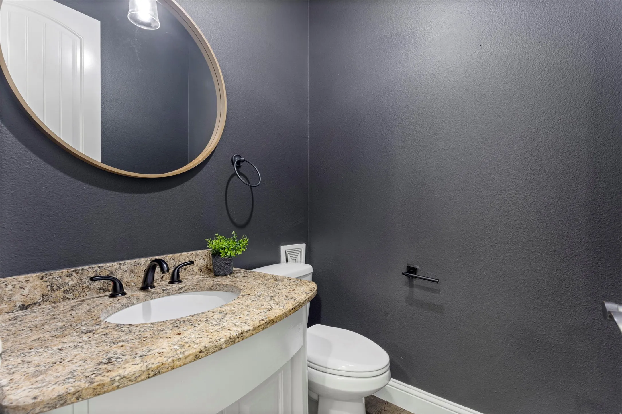 Bathroom featuring a vanity with an undermount sink, a patterned stone countertop, and matte black fixtures