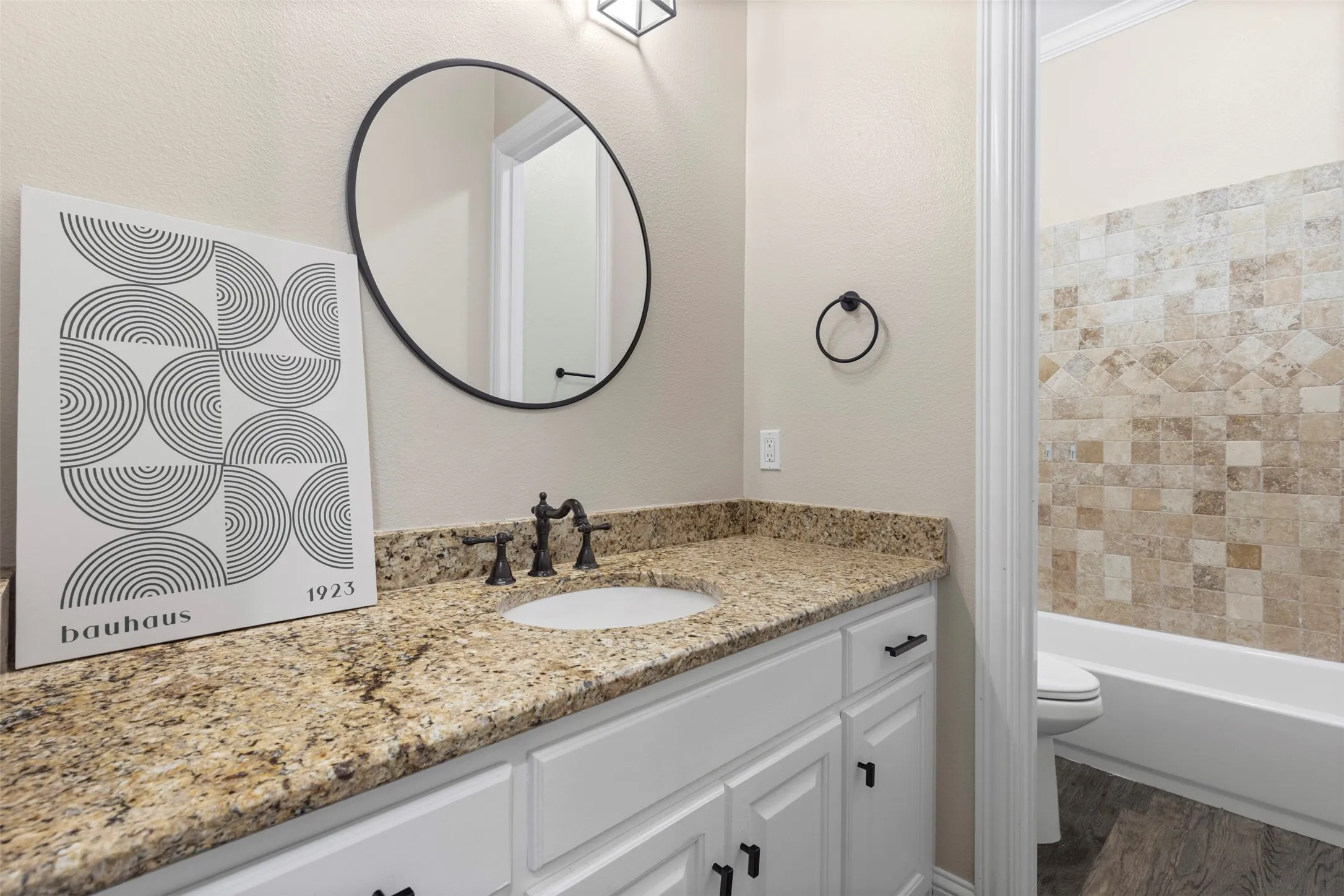 Granite countertop vanity with integrated sink, white cabinetry, and oil-rubbed bronze fixtures