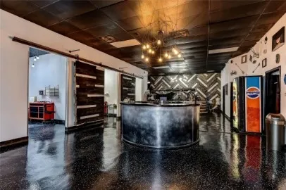 Spacious interior featuring high-gloss black flooring, a textured black ceiling, and a prominent industrial-style reception desk