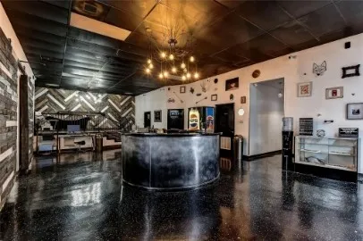 Spacious interior featuring dark, reflective flooring, a prominent circular counter, and a ceiling with exposed light fixtures