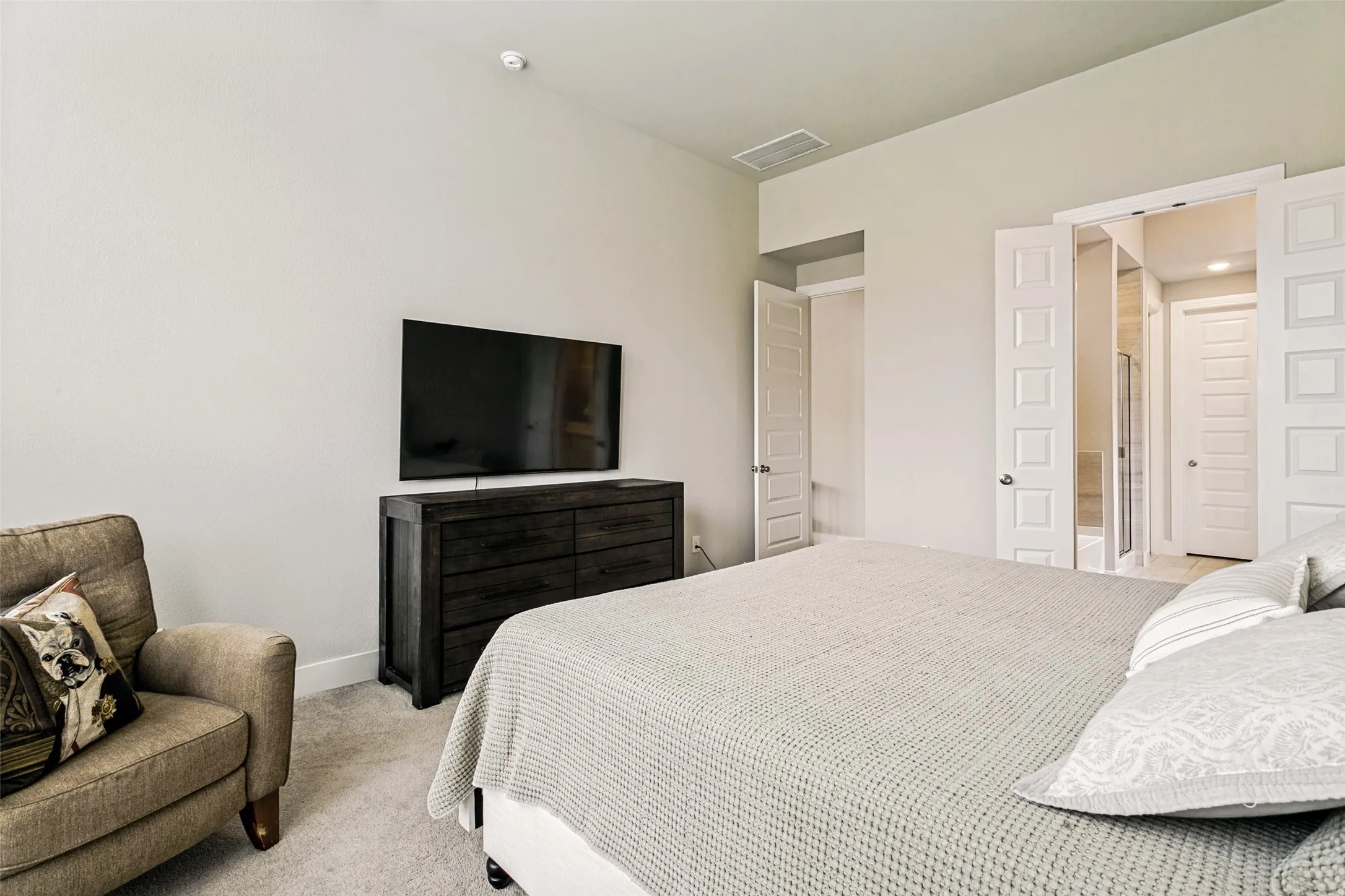 Bedroom featuring light-toned walls, plush carpeting, and multiple white panel doors