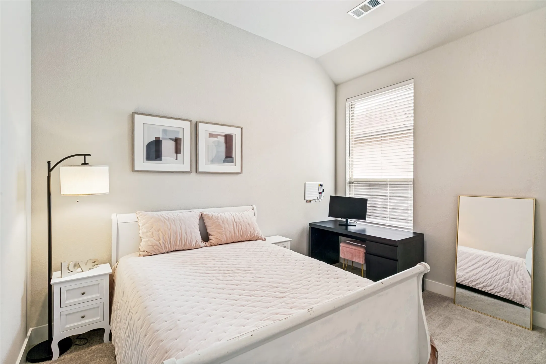 Light-filled interior featuring a single window with blinds, vaulted ceilings, and neutral wall paint