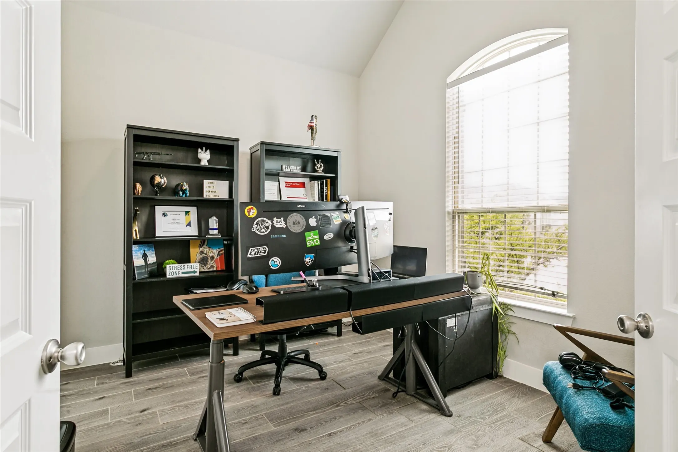 Arch-top window with blinds, wood-finish flooring, and crisp white walls