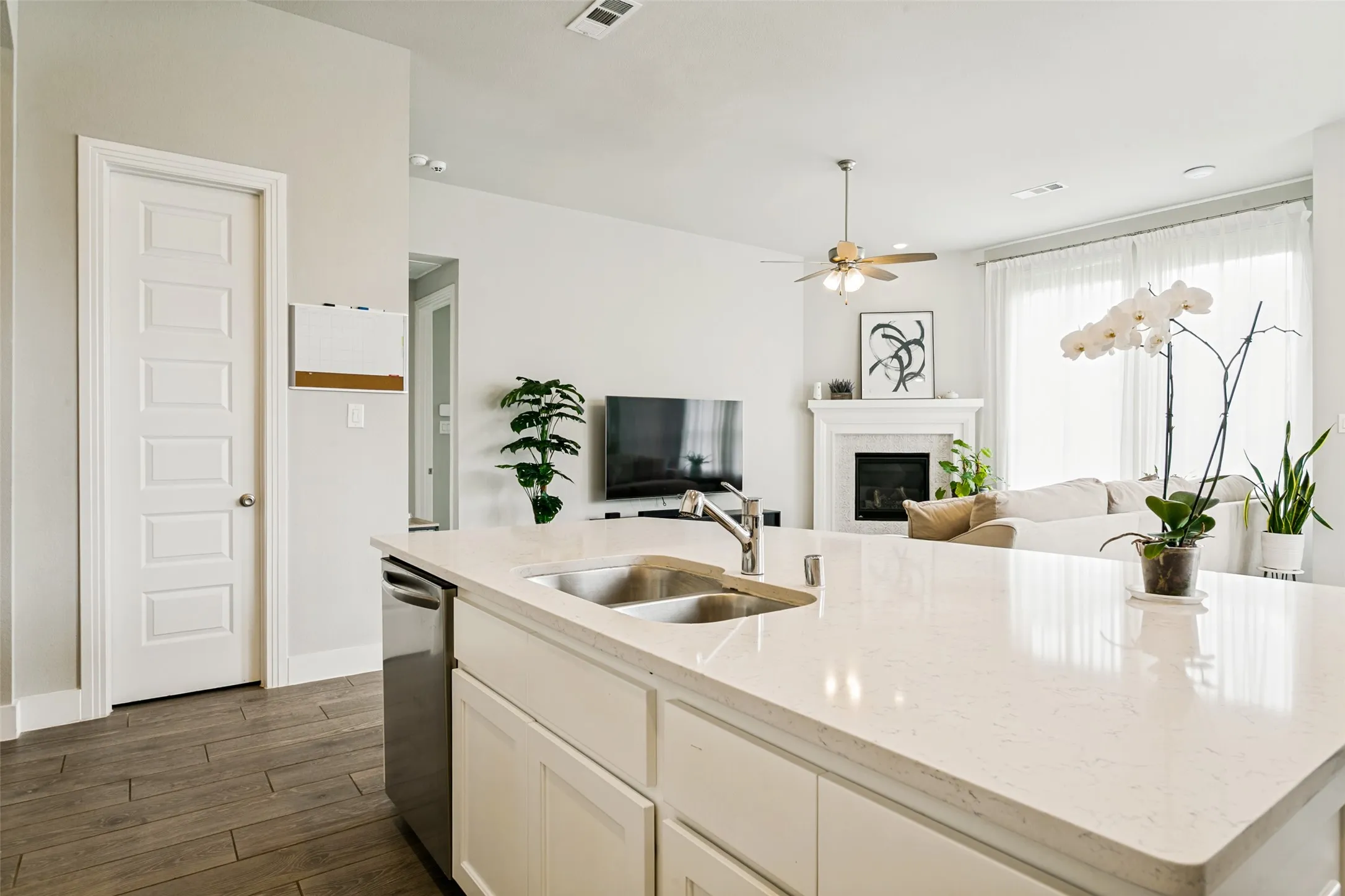 Spacious kitchen island featuring a dual basin sink, integrated dishwasher, and light-colored countertop