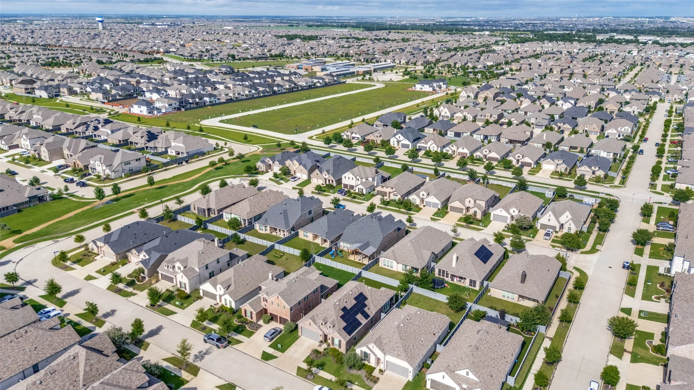 Aerial overview of a residential development featuring uniform setbacks, consistent architectural styling, multiple roof styles, and solar panel installations on some residences