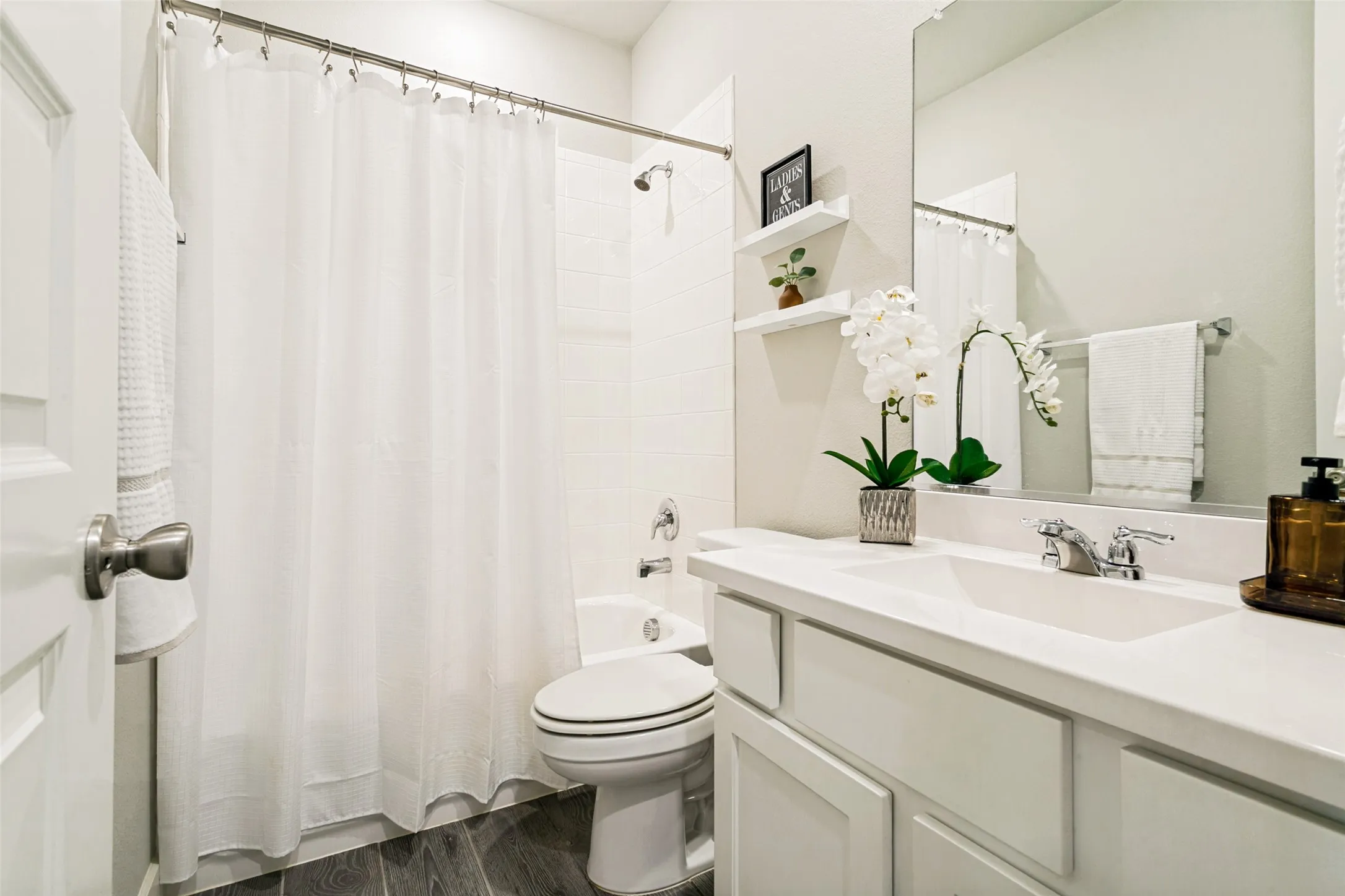 Bathroom featuring a white vanity with integrated sink, chrome faucet, and expansive mirror
