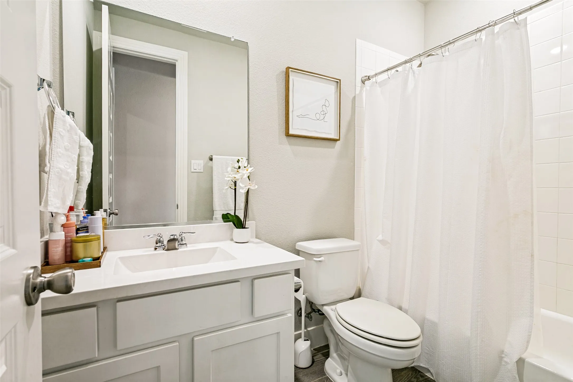Bathroom featuring a white vanity with an integrated sink, polished chrome faucet, and expansive wall mirror