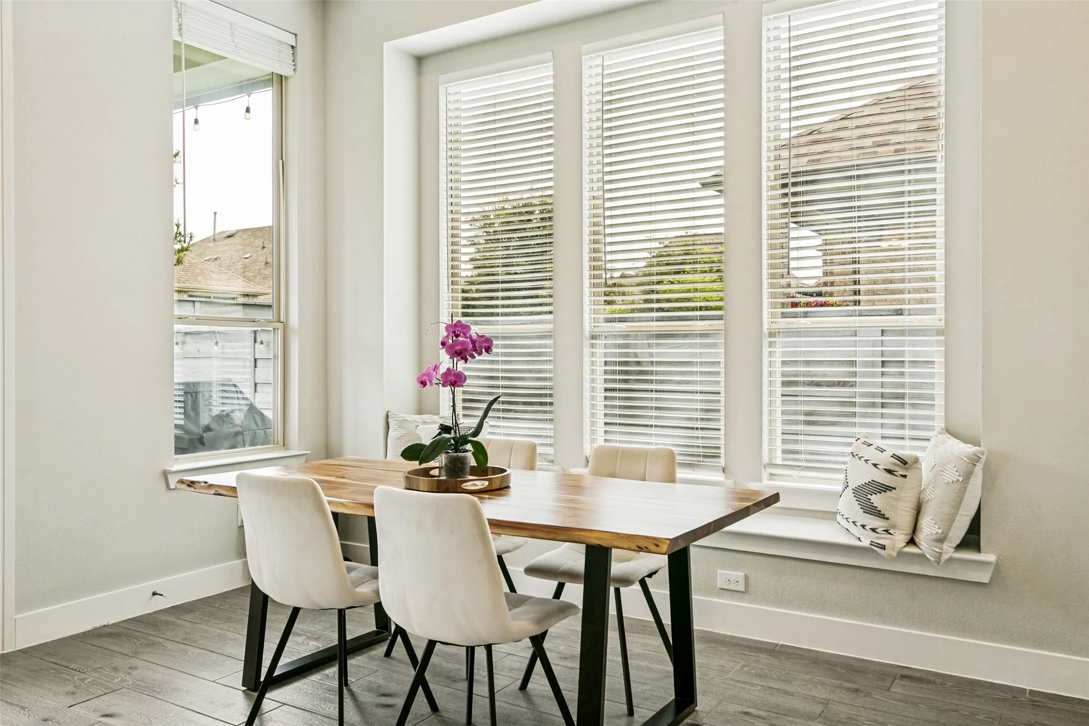 Dining area featuring a large window array with blinds, wood-finish flooring, and a built-in window bench