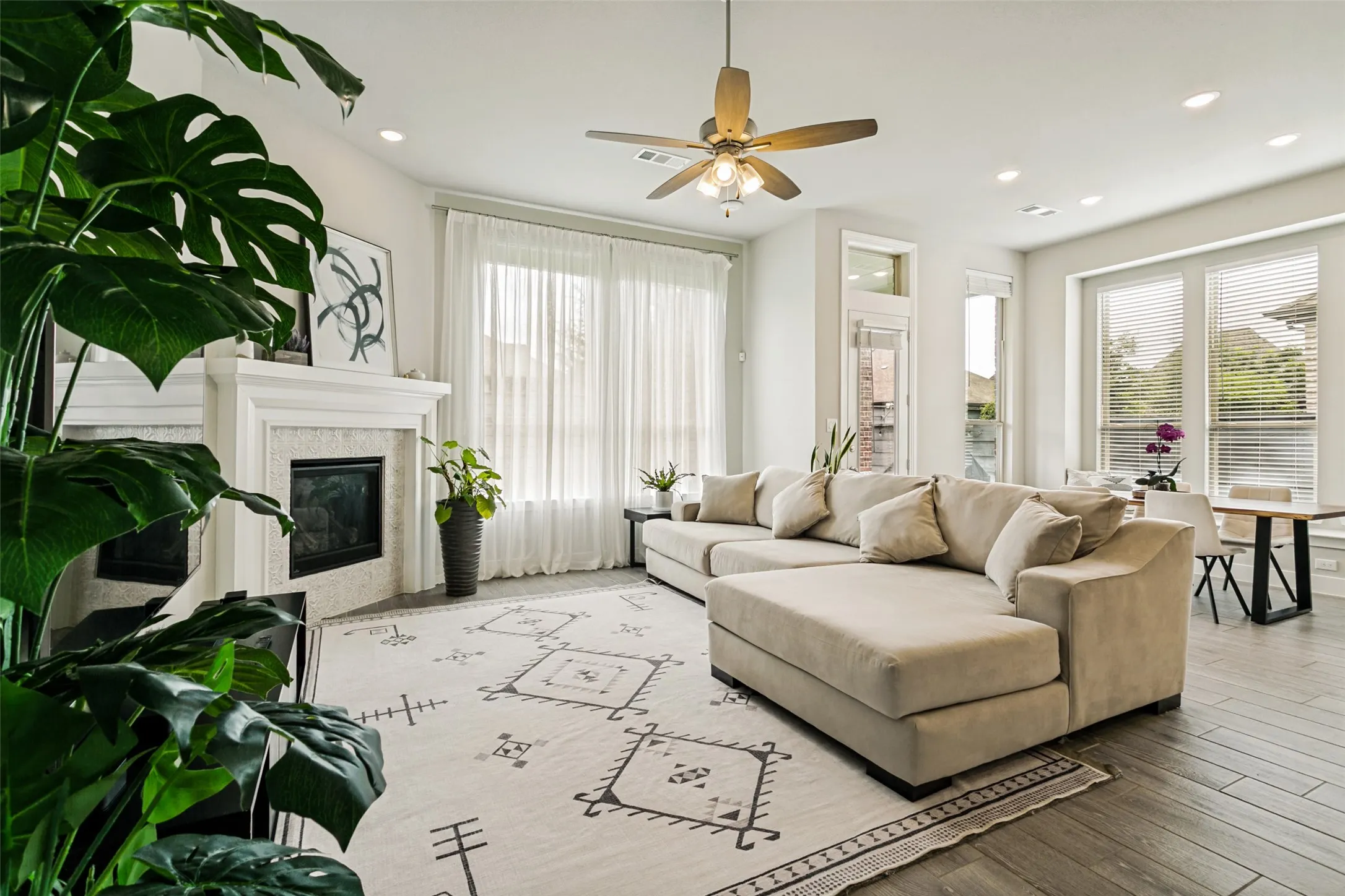 Spacious living area featuring wood-finish flooring, a decorative fireplace with a mantel, recessed lighting, and a ceiling fan
