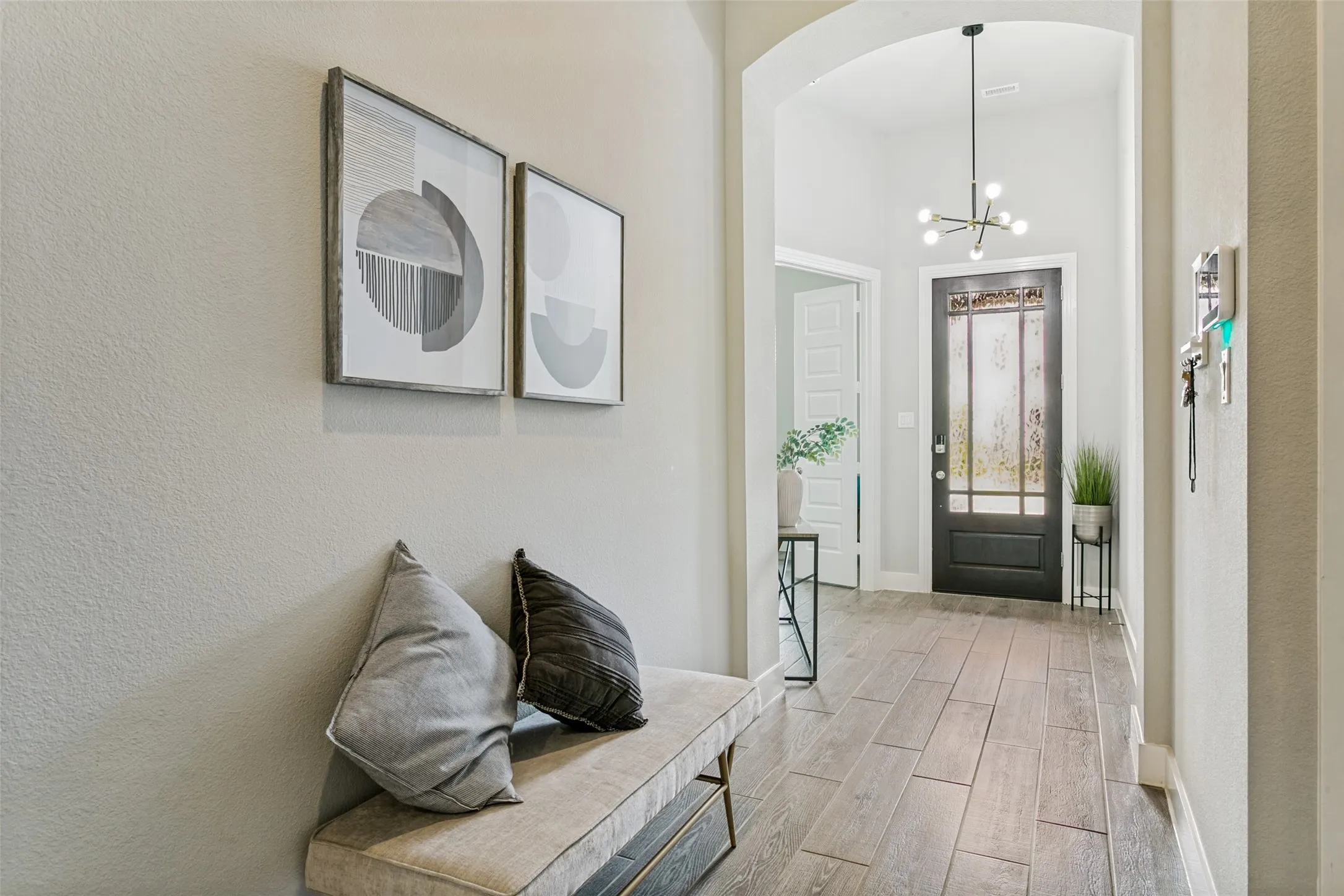 Foyer featuring wood-finish flooring, an arched entryway, and a decorative front door with frosted glass panels
