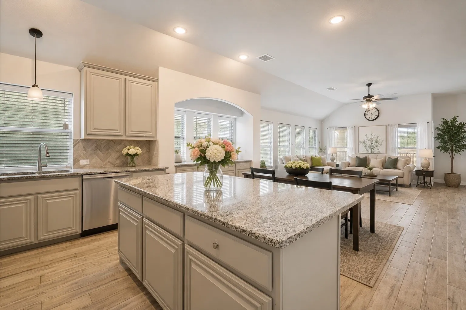 Open-concept living space featuring a kitchen island with granite countertops, stainless steel appliances, wood-finish flooring, recessed lighting, and a vaulted ceiling in the living area