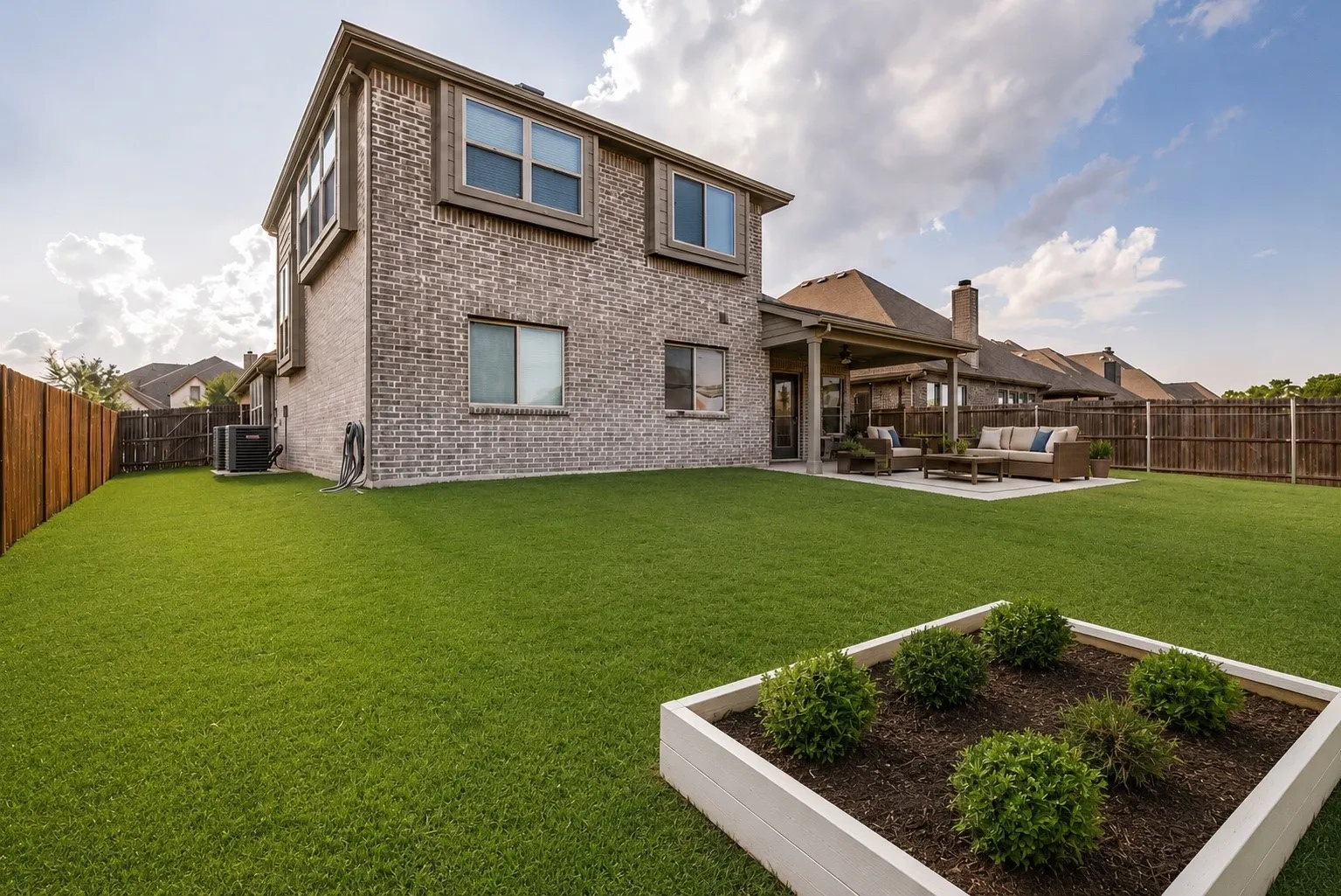 Expansive backyard featuring a lush green lawn and a covered patio
