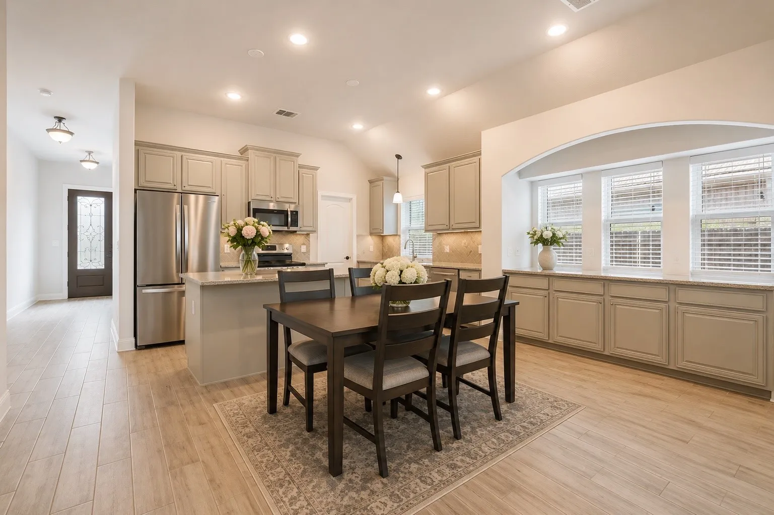 Open-concept kitchen and dining area featuring light wood-finish flooring, recessed lighting, and a vaulted ceiling