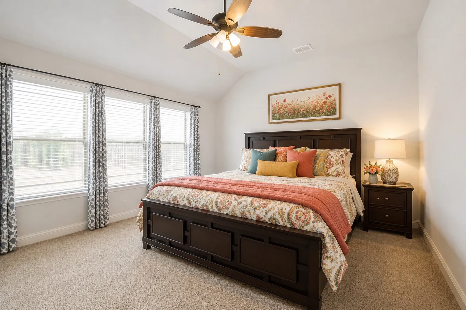 Vaulted ceiling bedroom featuring plush carpet flooring, a three-panel window ensemble with blinds, and a ceiling fan with integrated lighting