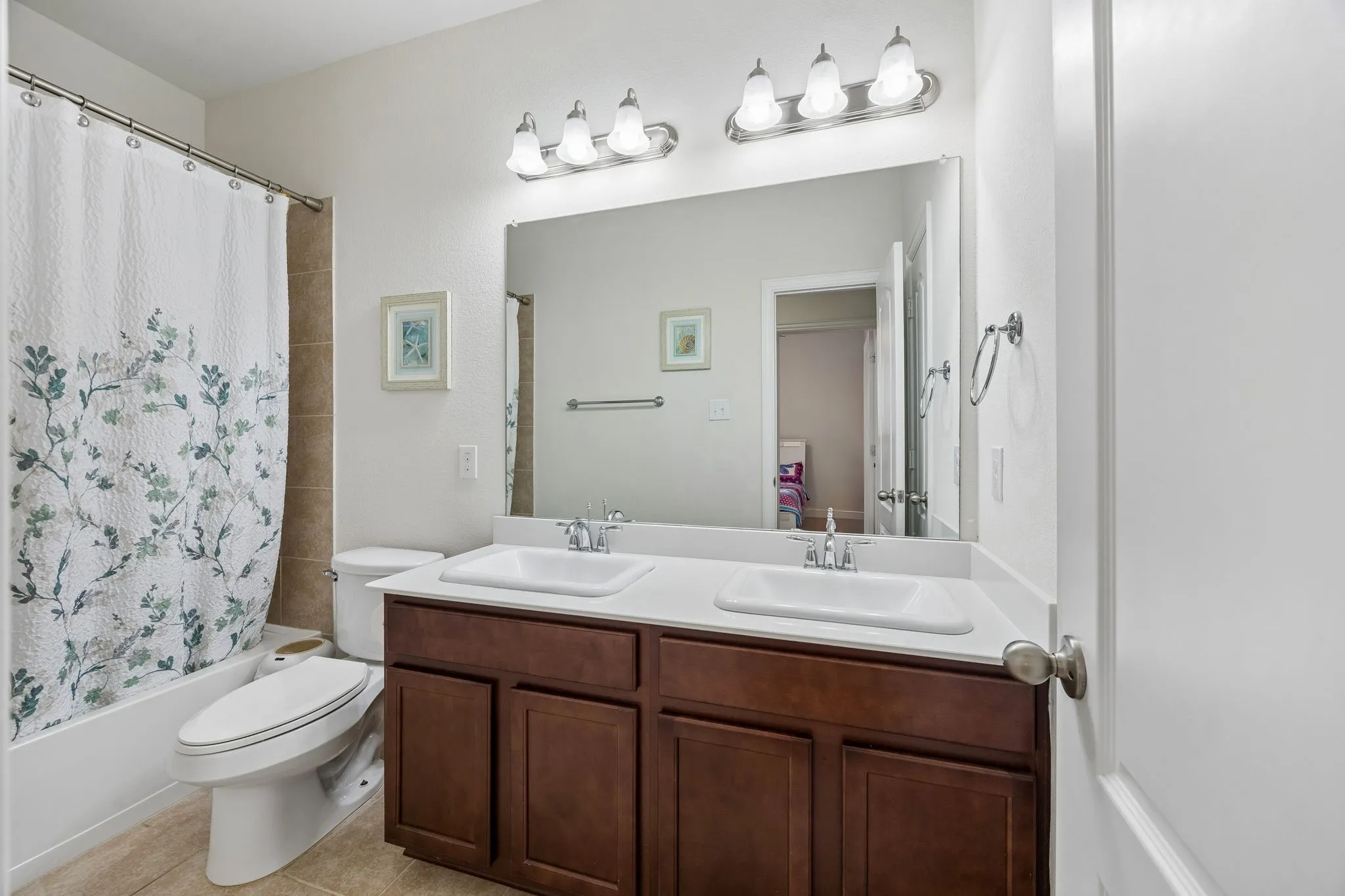Bathroom featuring a vanity with 2 sinks and a tub-shower combination. Easy access to living area and both secondary bedrooms.
