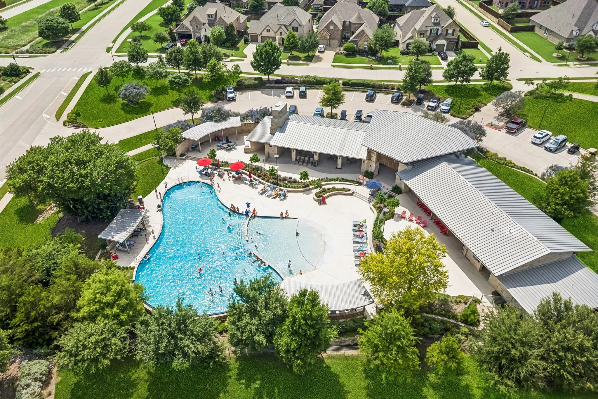 Community amenity center featuring a large swimming pool with beach entry and a community building