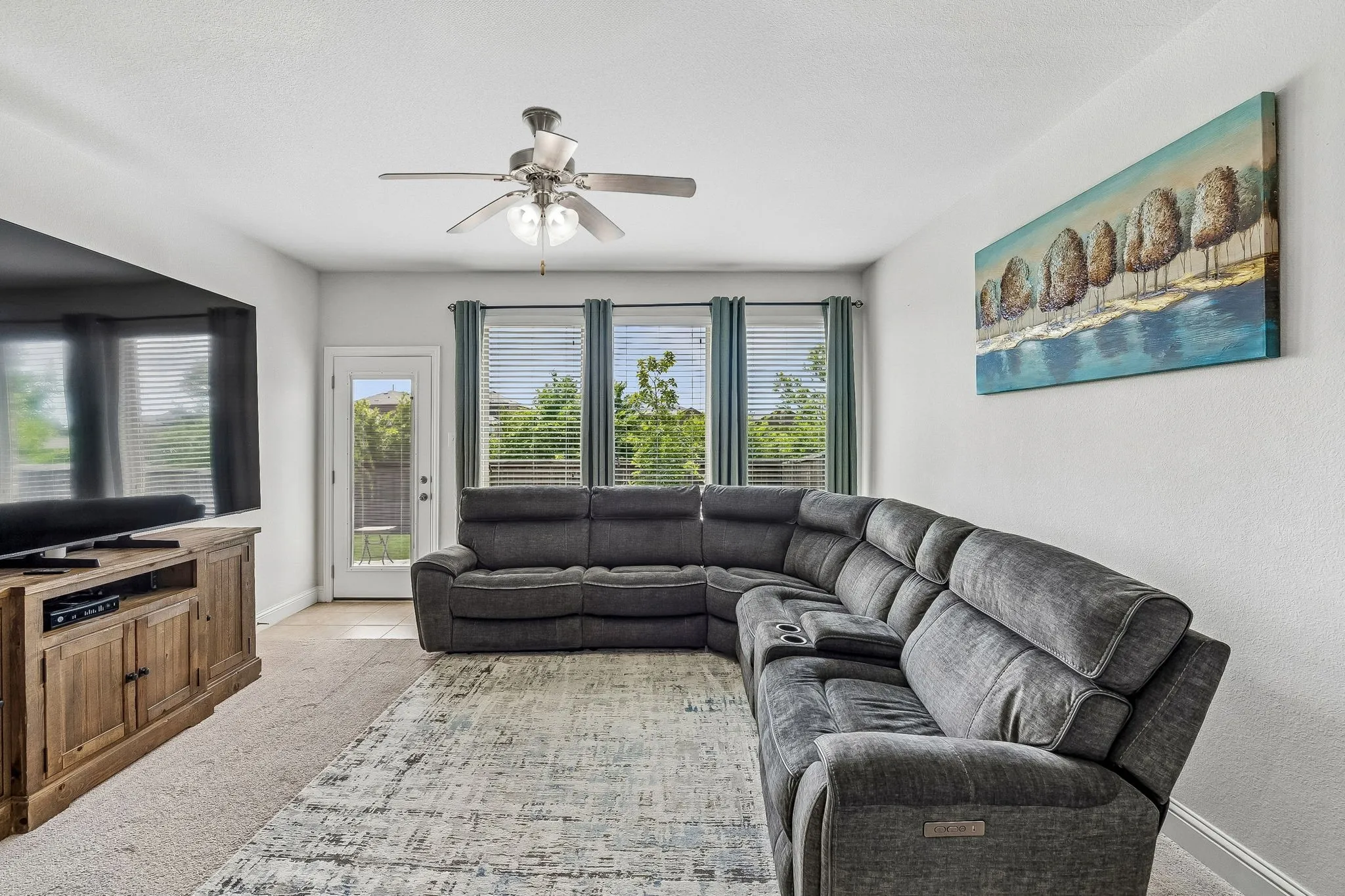 Living area with neutral-toned walls, ceiling fan with integrated lighting, and carpet flooring