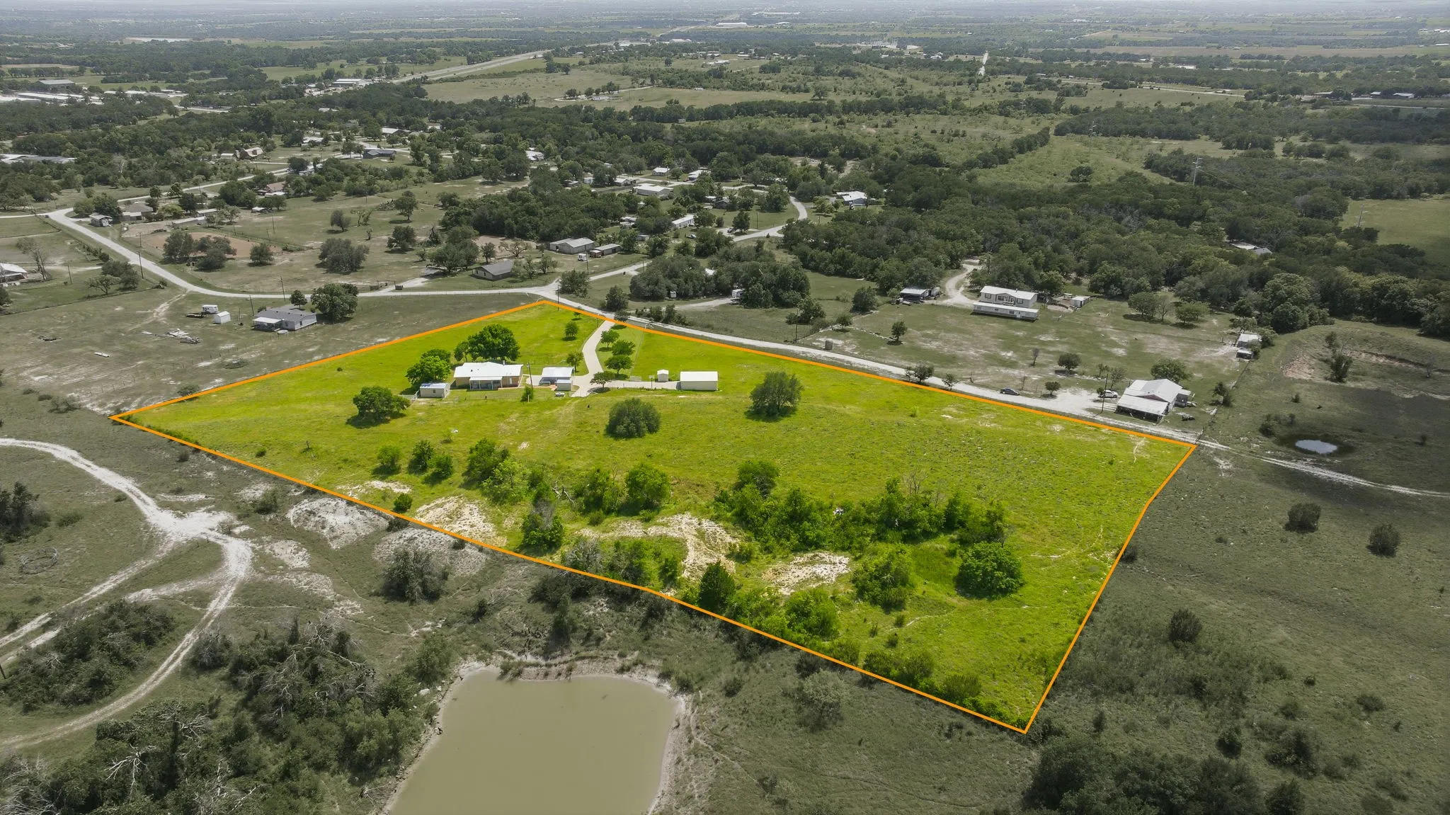 Expansive acreage featuring a main residence, multiple auxiliary structures, and a sizable natural pond