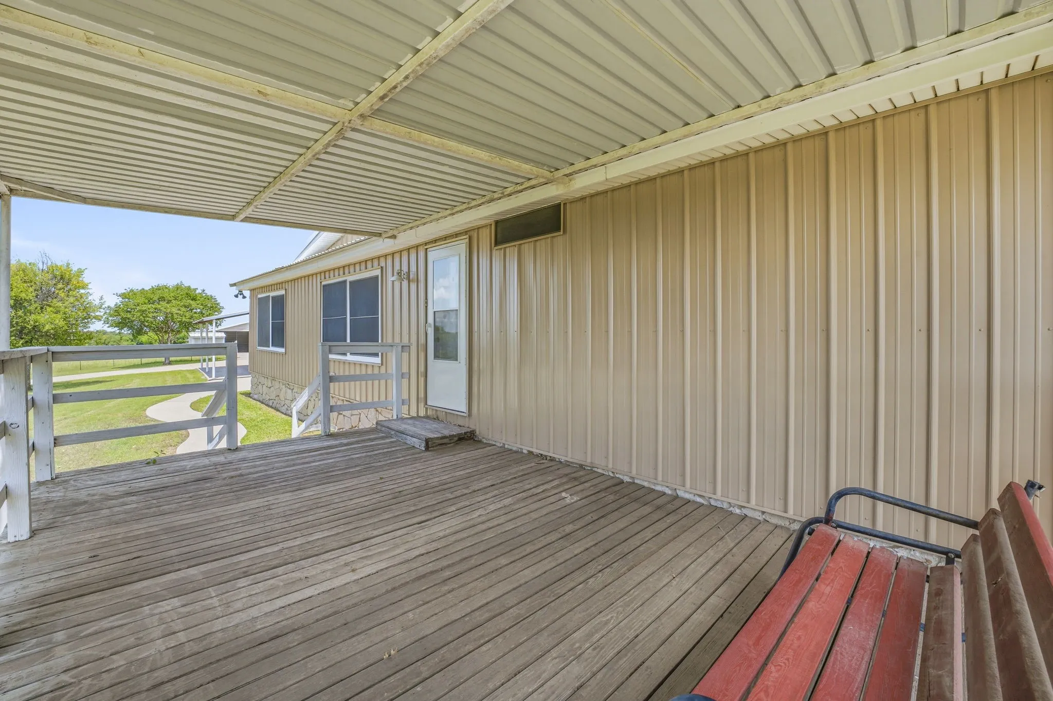 Covered wooden deck featuring a metal awning and painted railings