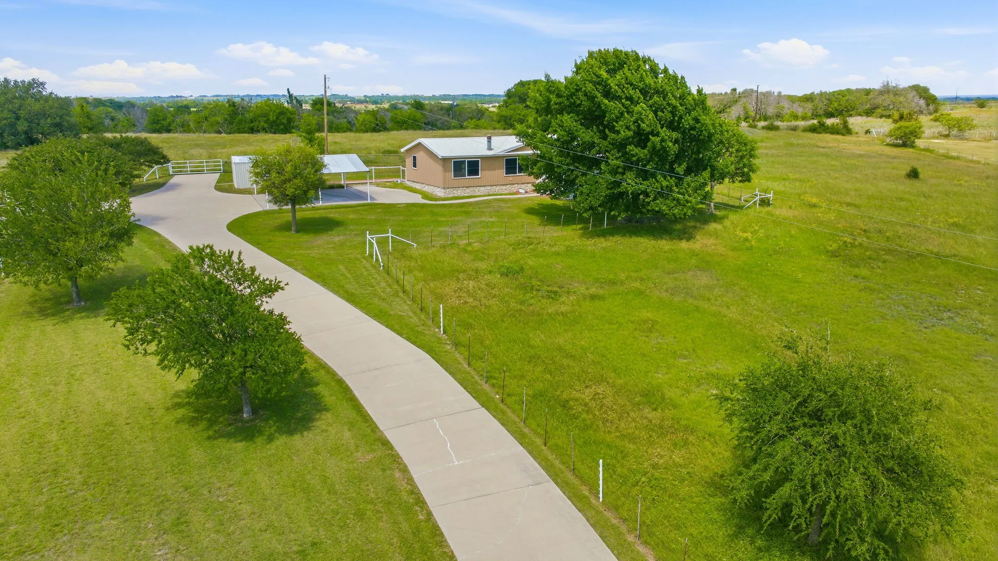 Expansive green property with a concrete driveway leading to a single-story residence