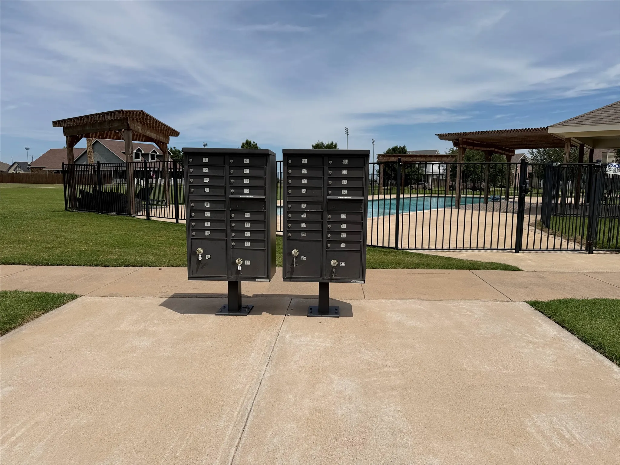 Community mailboxes with a nearby fenced swimming pool