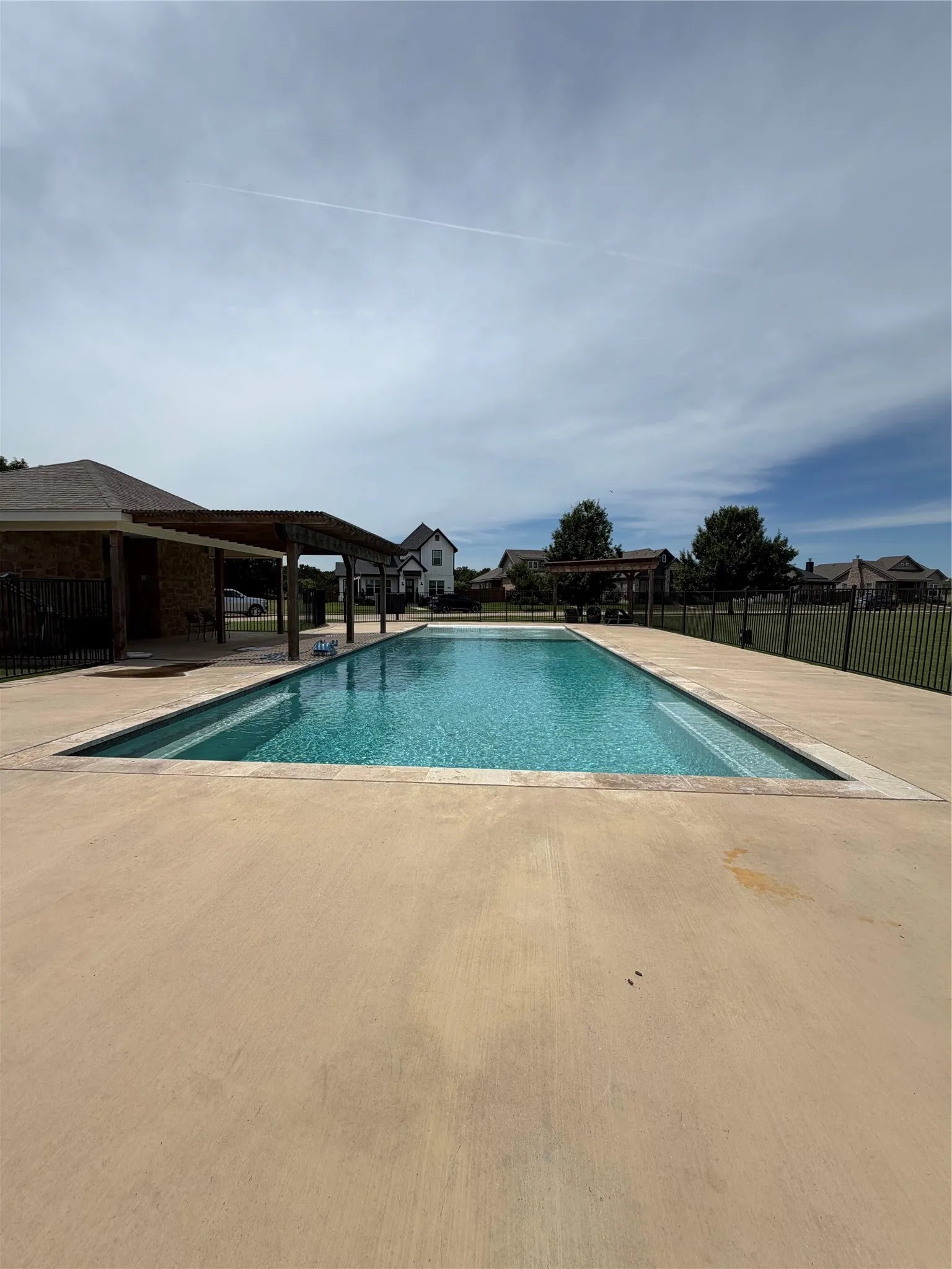 Rectangular swimming pool with a surrounding  black metal fence
