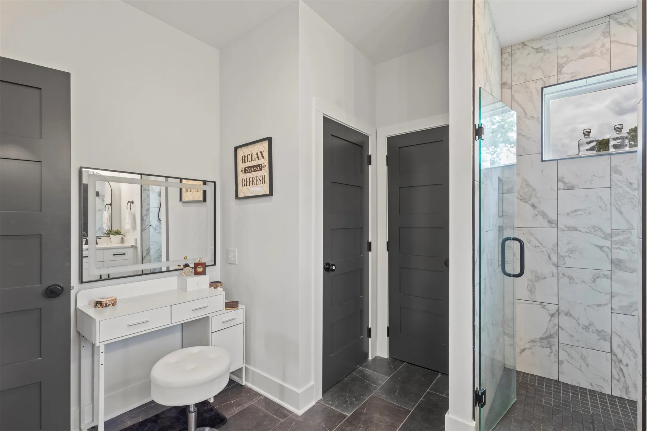 Spa-inspired primary bath featuring dual vanities, designer lighting, sleek black hardware, and a spacious walk-in shower with refined tilework—creating a polished, luxury retreat with modern country elegance.
