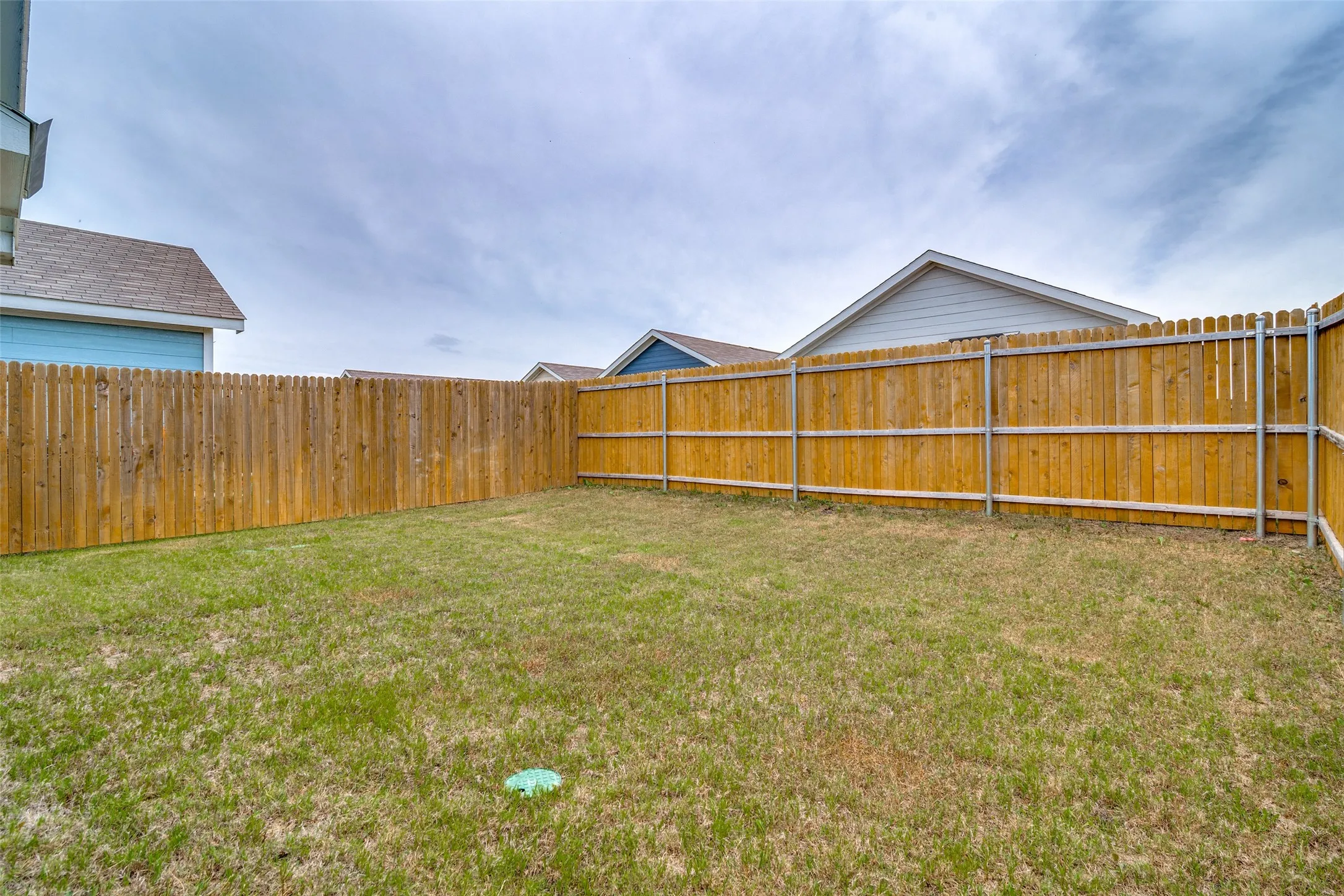 Private backyard space featuring a wood privacy fence with metal posts and a grass lawn