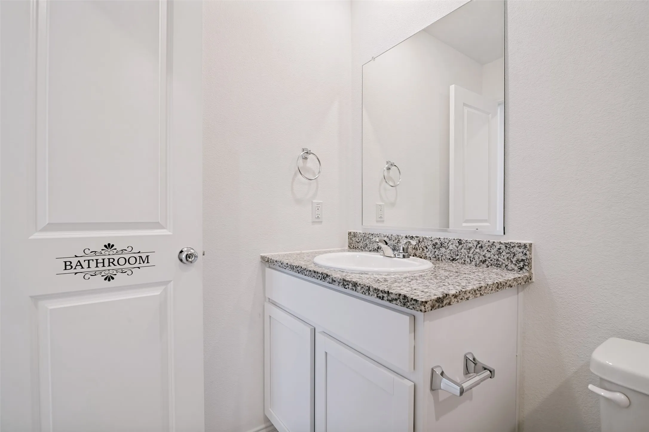Bathroom vanity with a granite countertop, undermount sink, and chrome fixtures