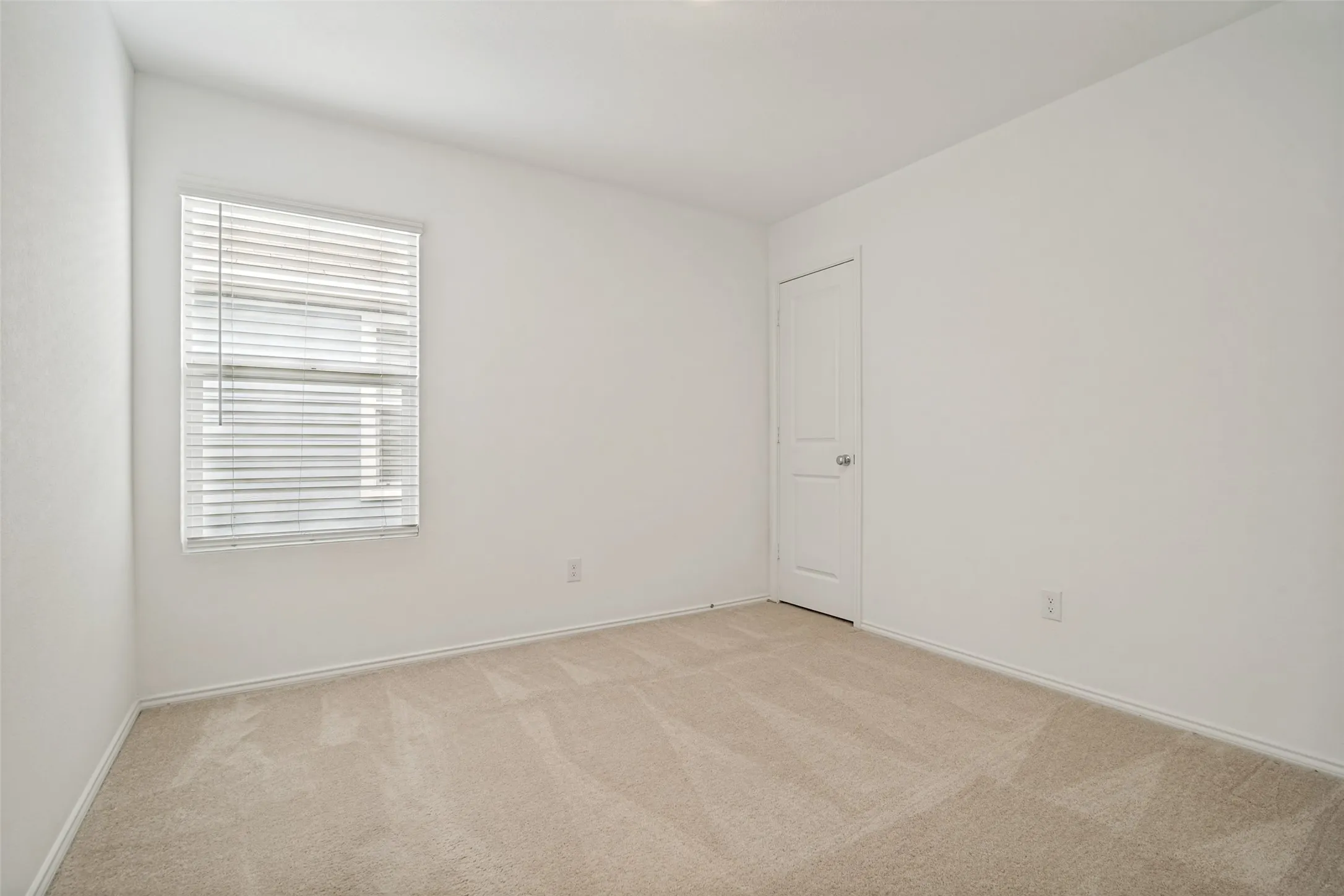 Room featuring neutral-toned carpet flooring, white walls, and a window with horizontal blinds