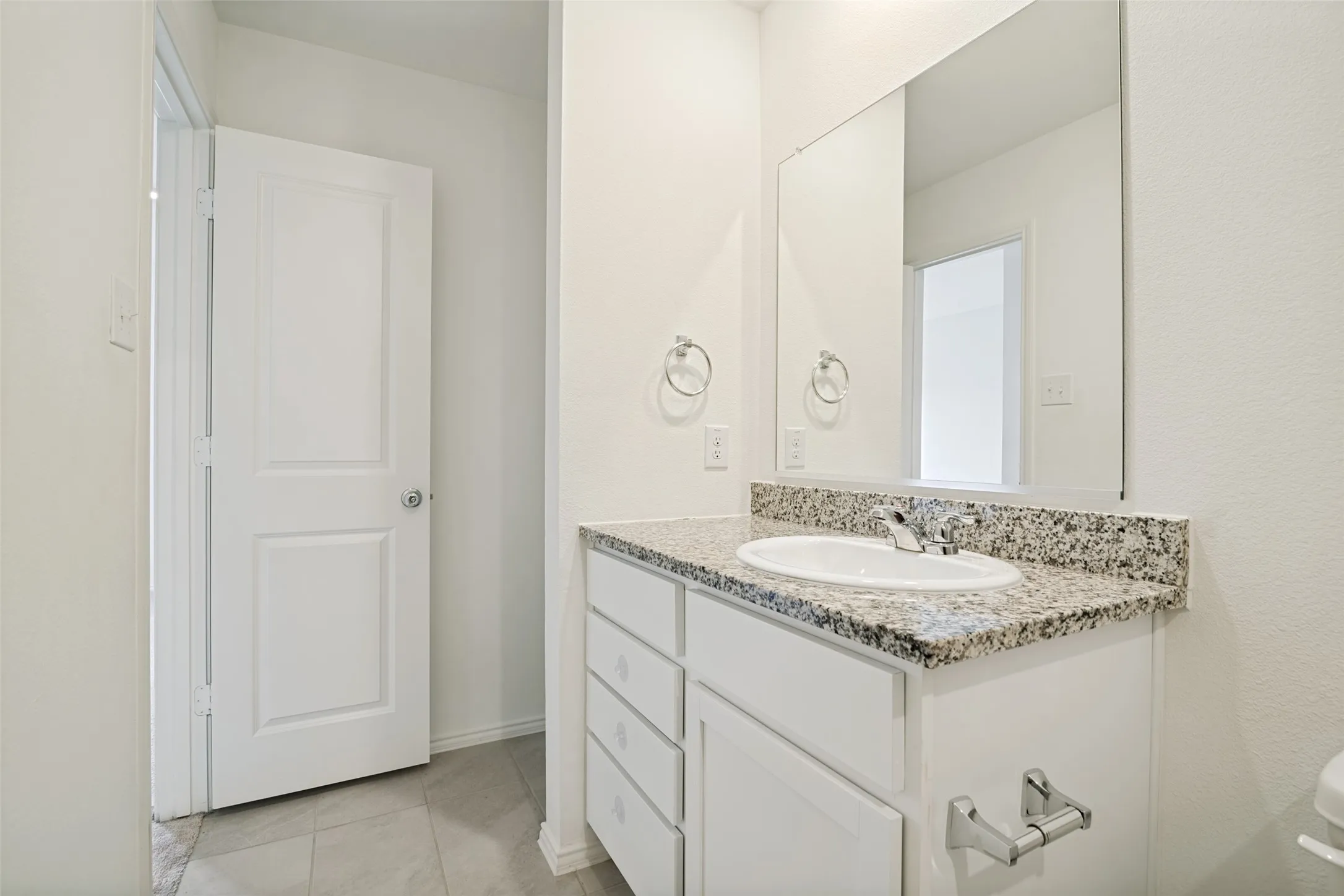 Bathroom vanity featuring a granite countertop, undermount sink, and chrome faucet