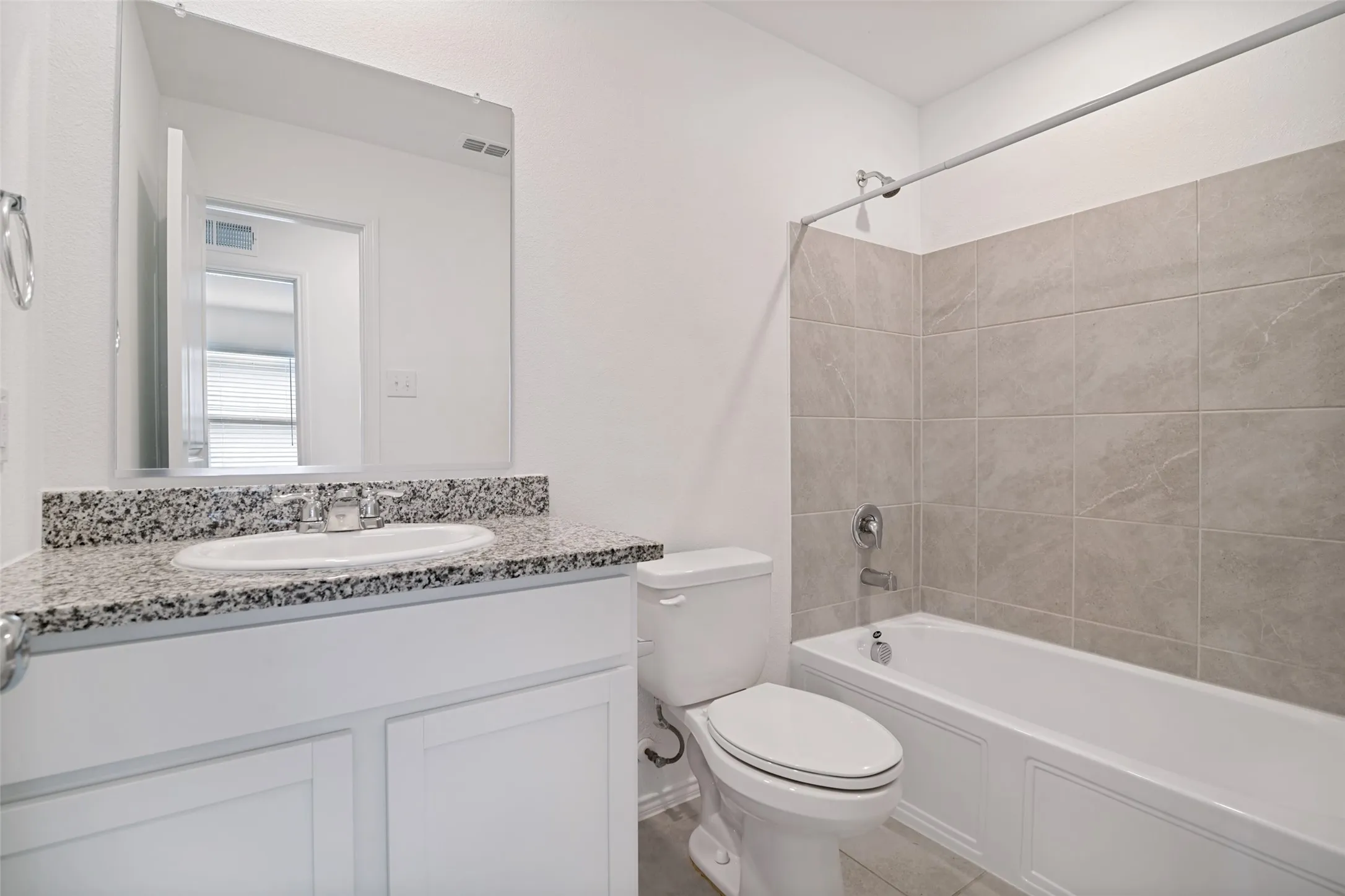 Bathroom featuring a granite-look countertop, white cabinetry, integrated sink, and a tiled shower-bath combination with chrome fixtures
