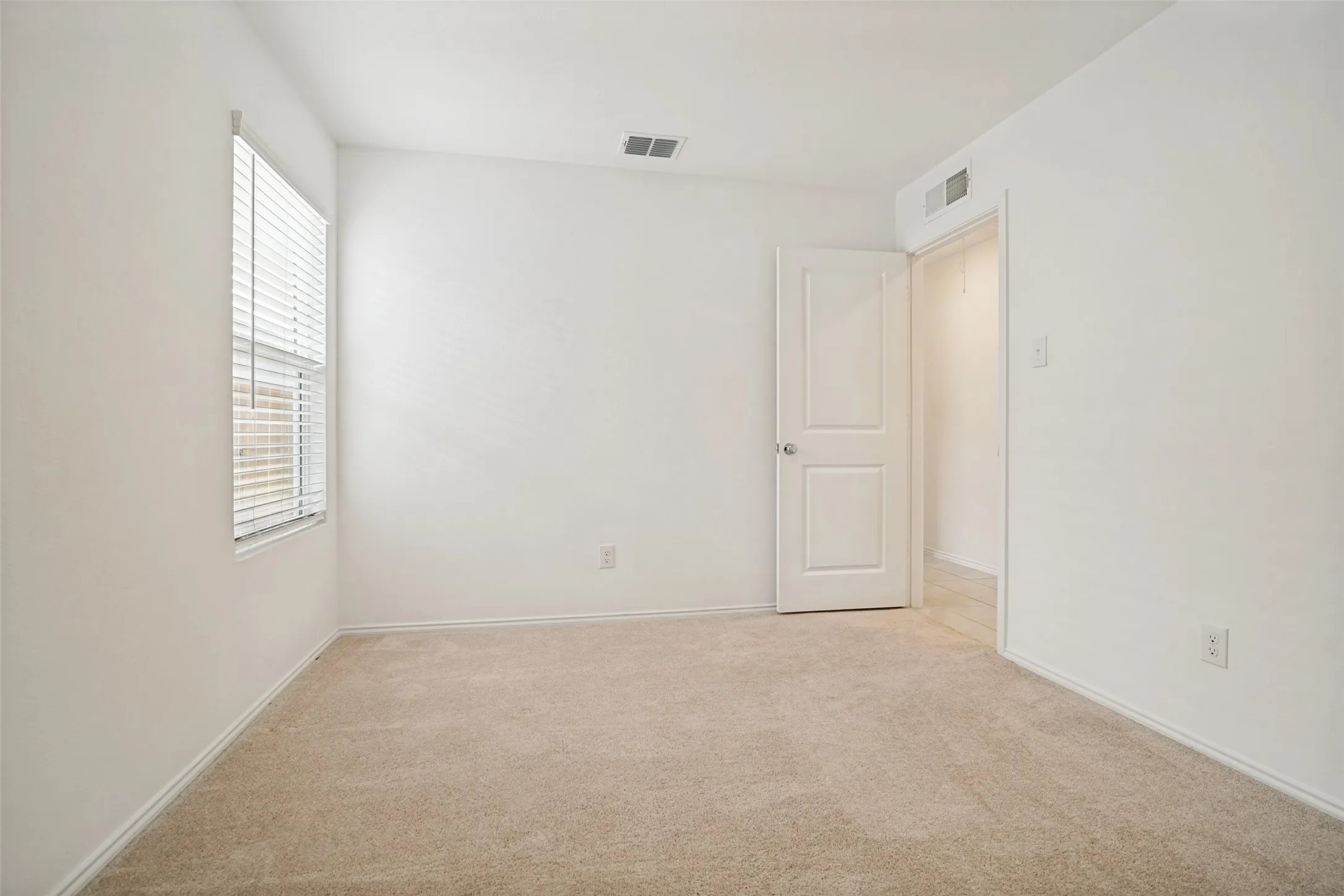 Carpeted room with a double-pane window featuring horizontal blinds