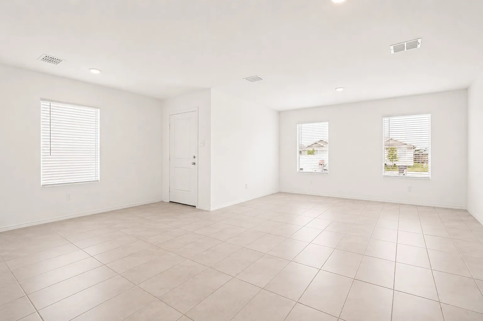 Spacious room featuring light-toned tile flooring, three windows with horizontal blinds, recessed lighting, and a neutral color palette