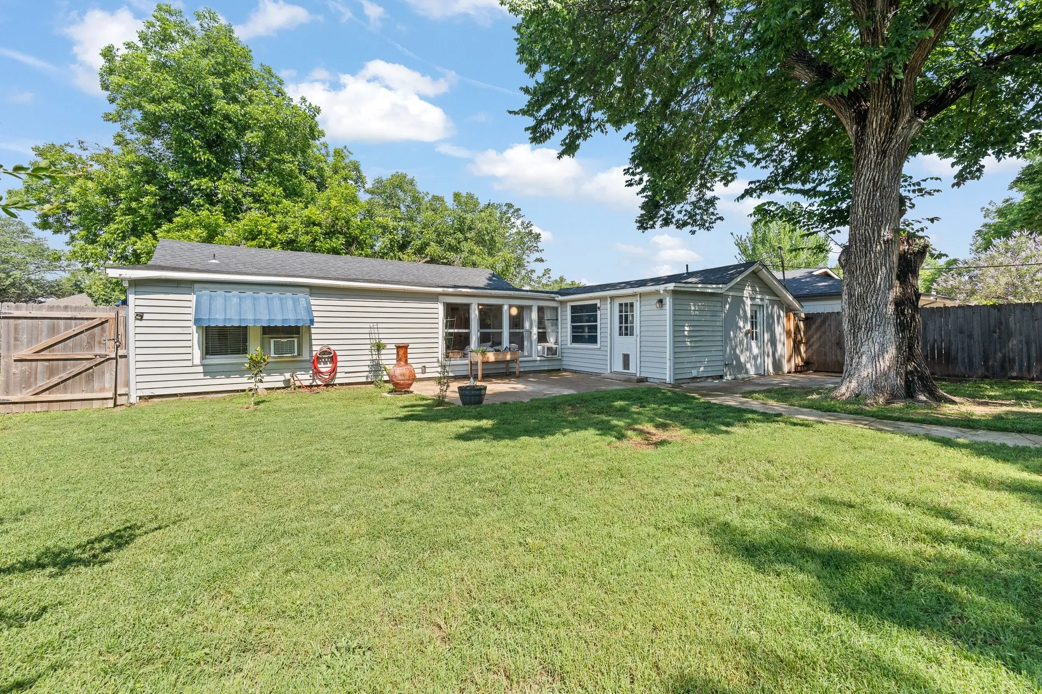 Expansive backyard featuring a green lawn, mature trees, and a wooden privacy fence