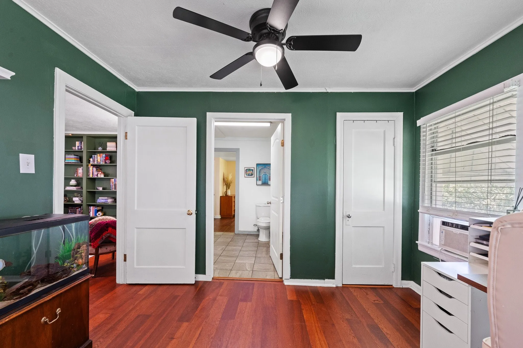 Room featuring rich wood-finish flooring, a ceiling fan with integrated lighting, and white trim work