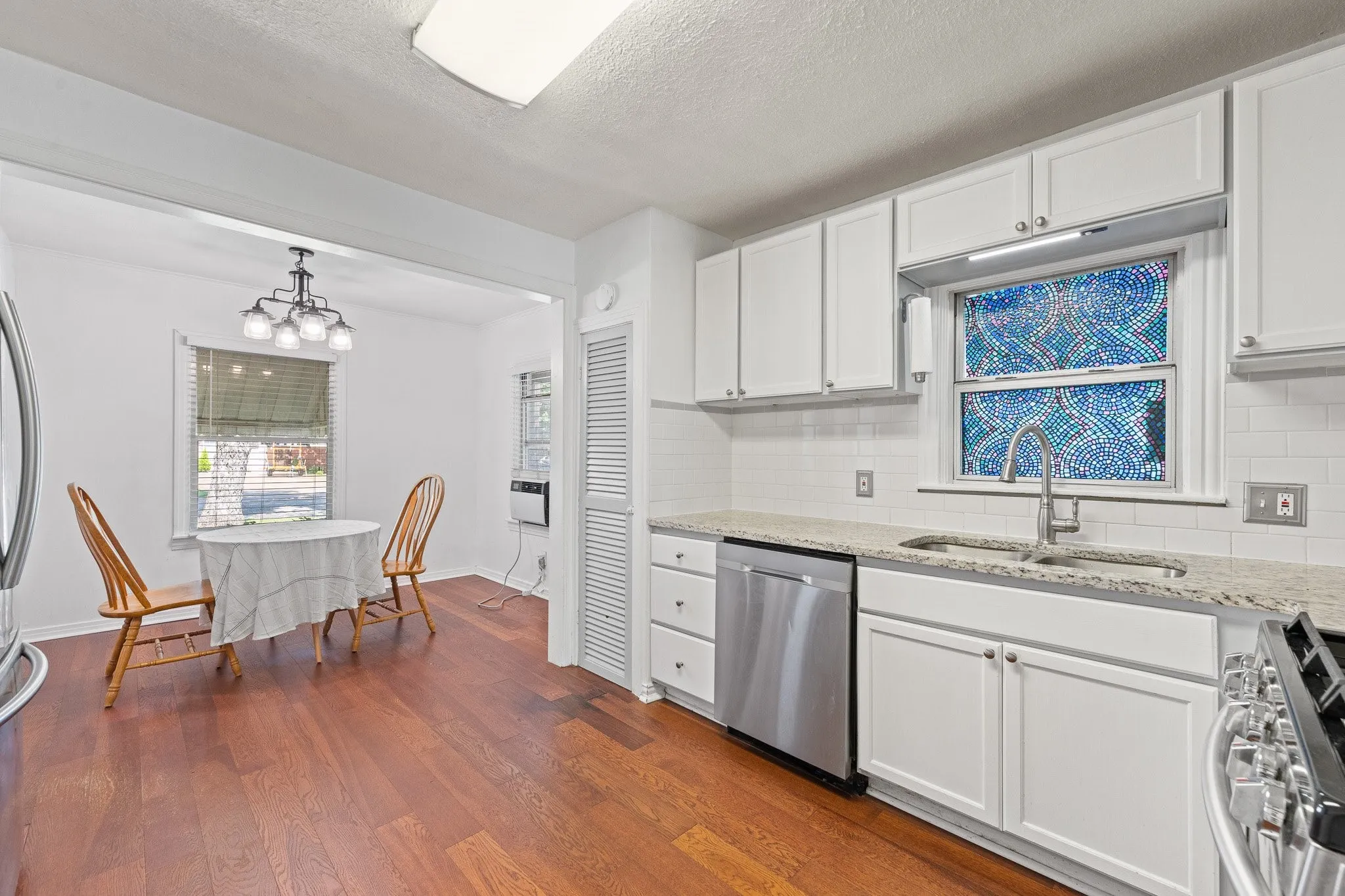 Modern kitchen featuring white cabinetry, granite countertops, and stainless steel appliances