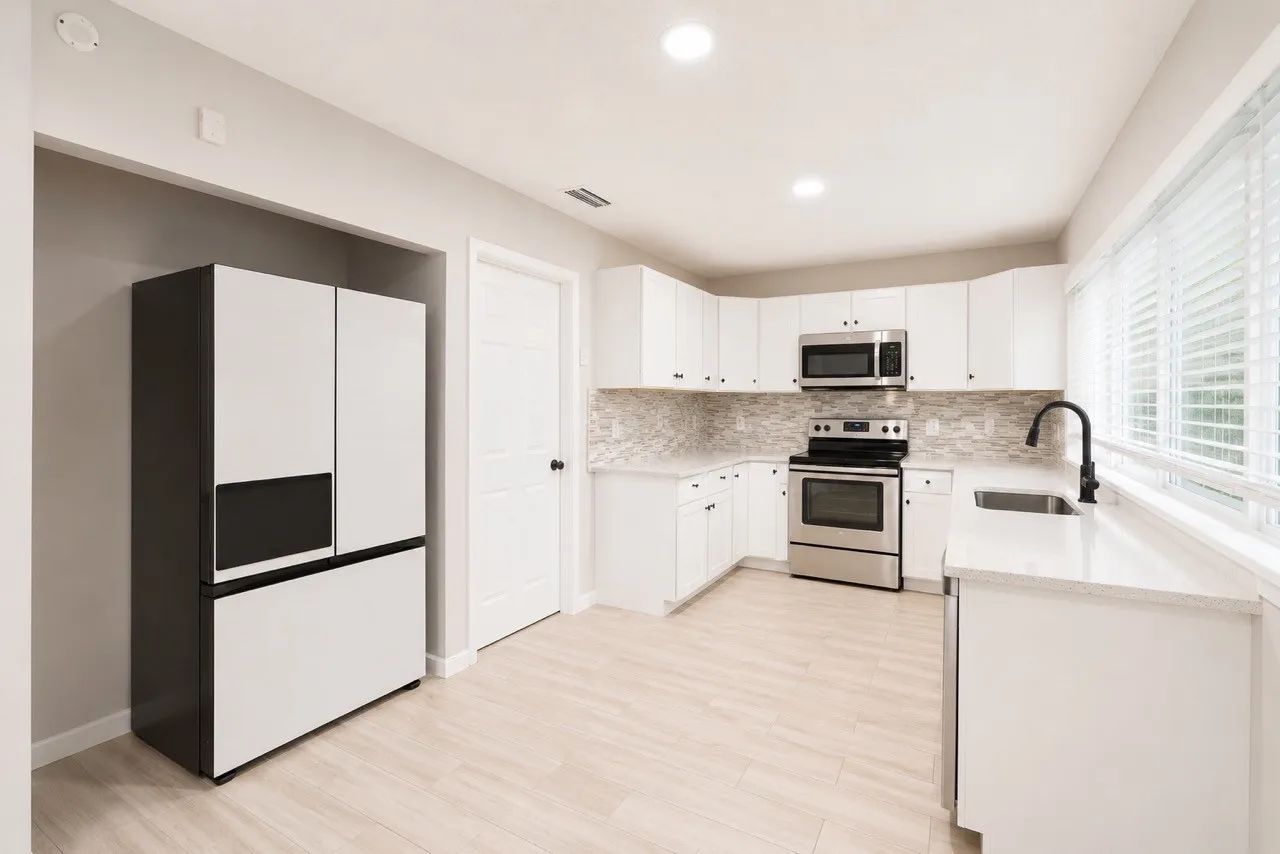 Contemporary kitchen featuring white cabinetry, light-toned countertops, and a mosaic tile backsplash