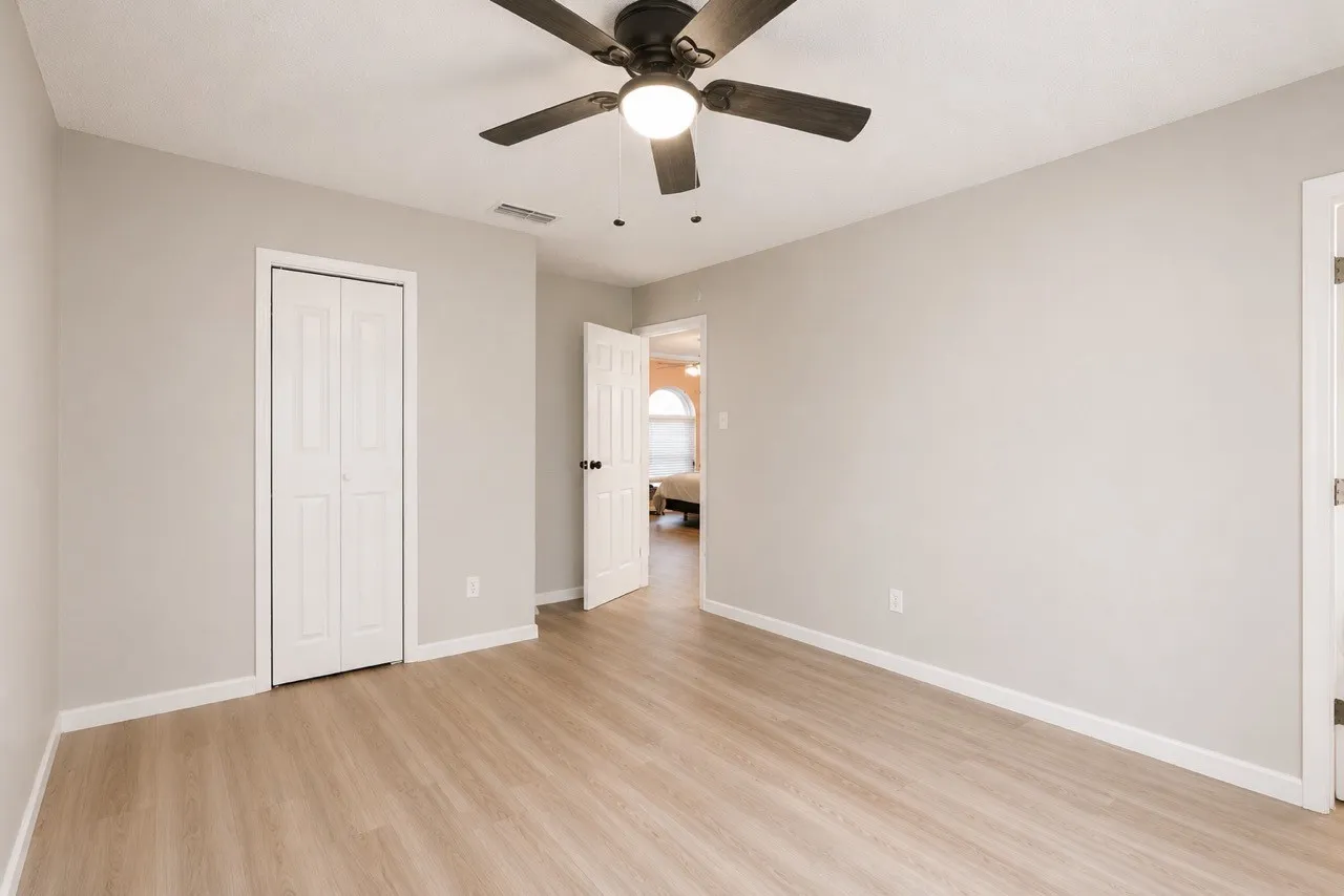 Spacious room featuring light wood-finish flooring, neutral wall paint, and white baseboards
