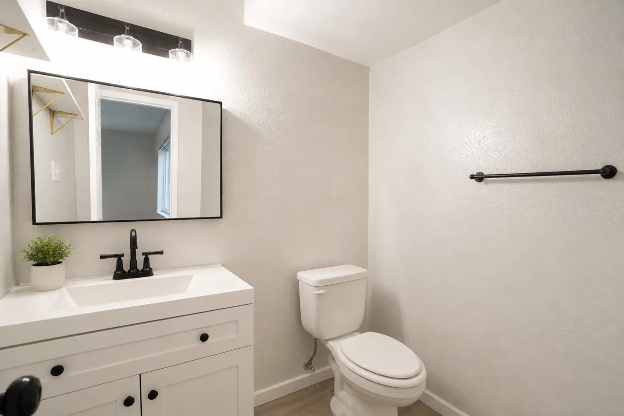Bathroom featuring a white vanity with recessed panel cabinetry and black hardware