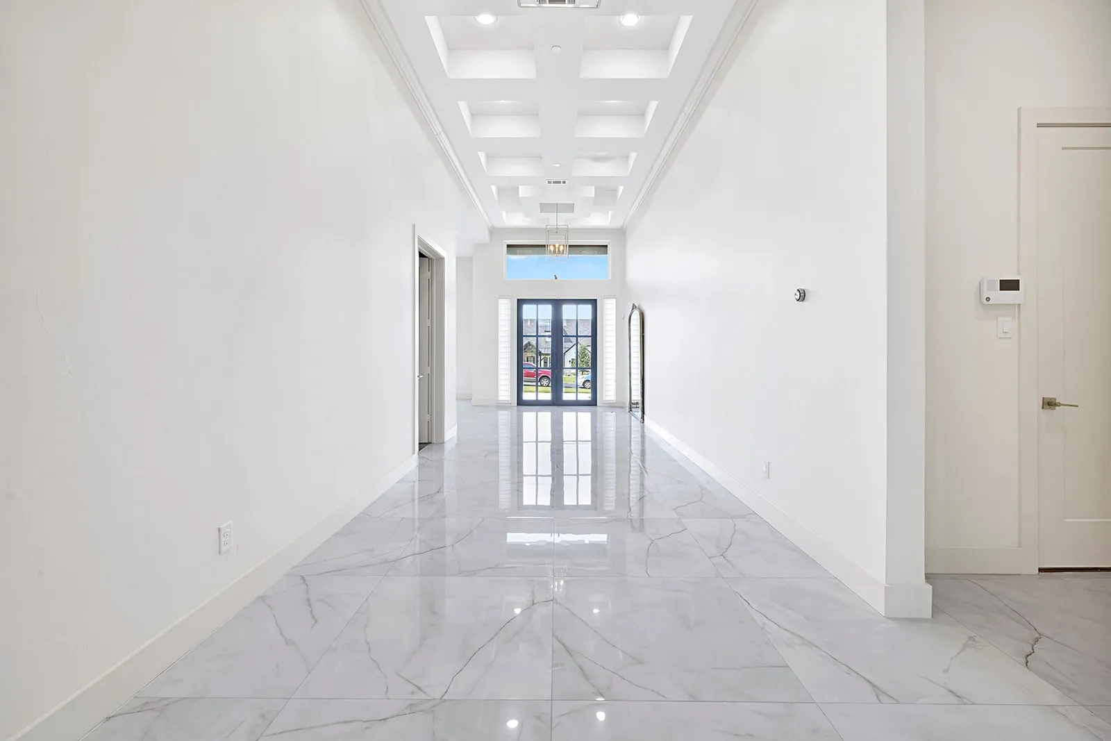 Long hallway with high ceilings featuring a coffered design and recessed lighting