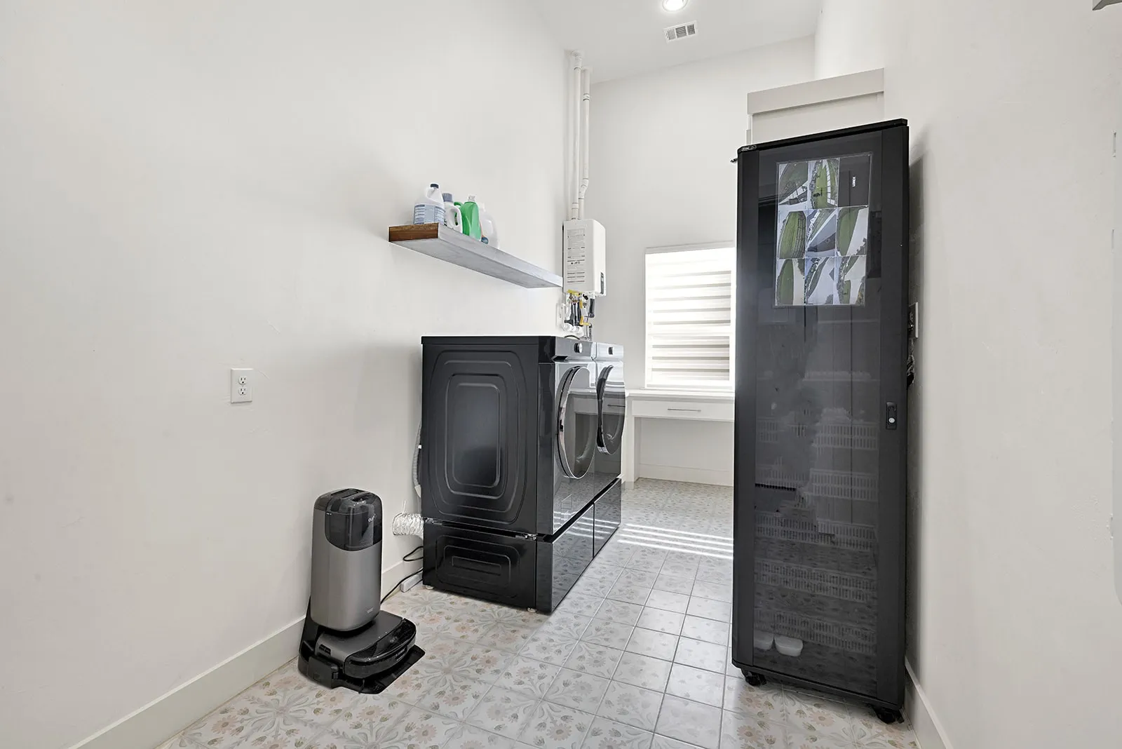 Laundry area featuring patterned floor tiles, a built-in desk with a window, and a wall-mounted floating shelf