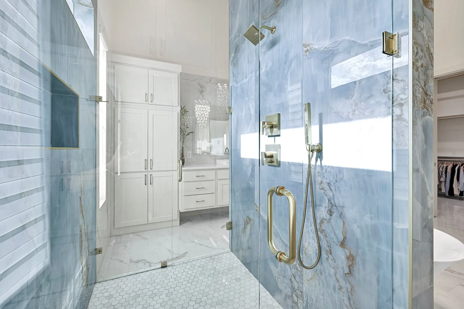 Expansive shower enclosure with glass walls and blue-toned stone paneling