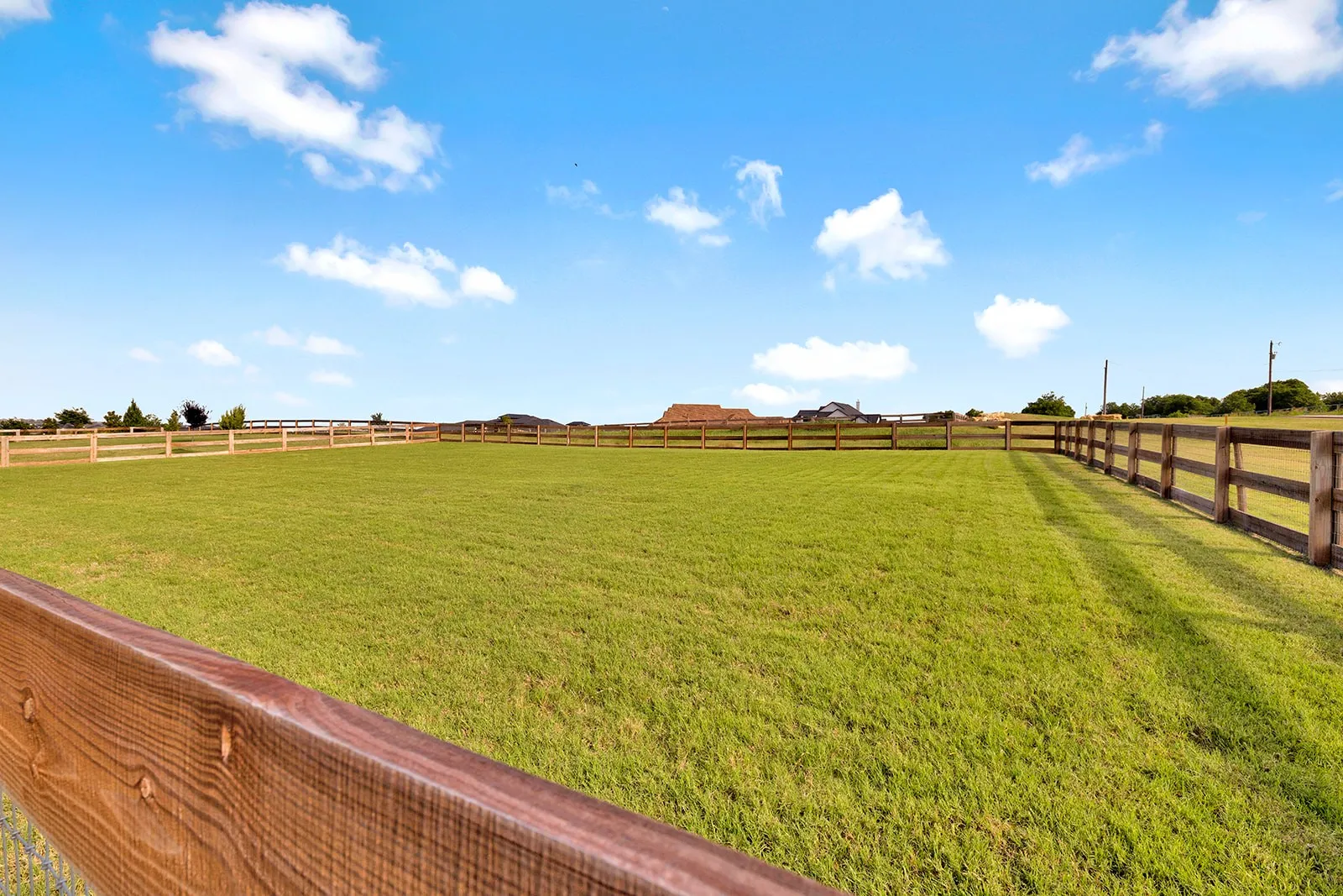 Expansive green space featuring a perimeter wooden fence