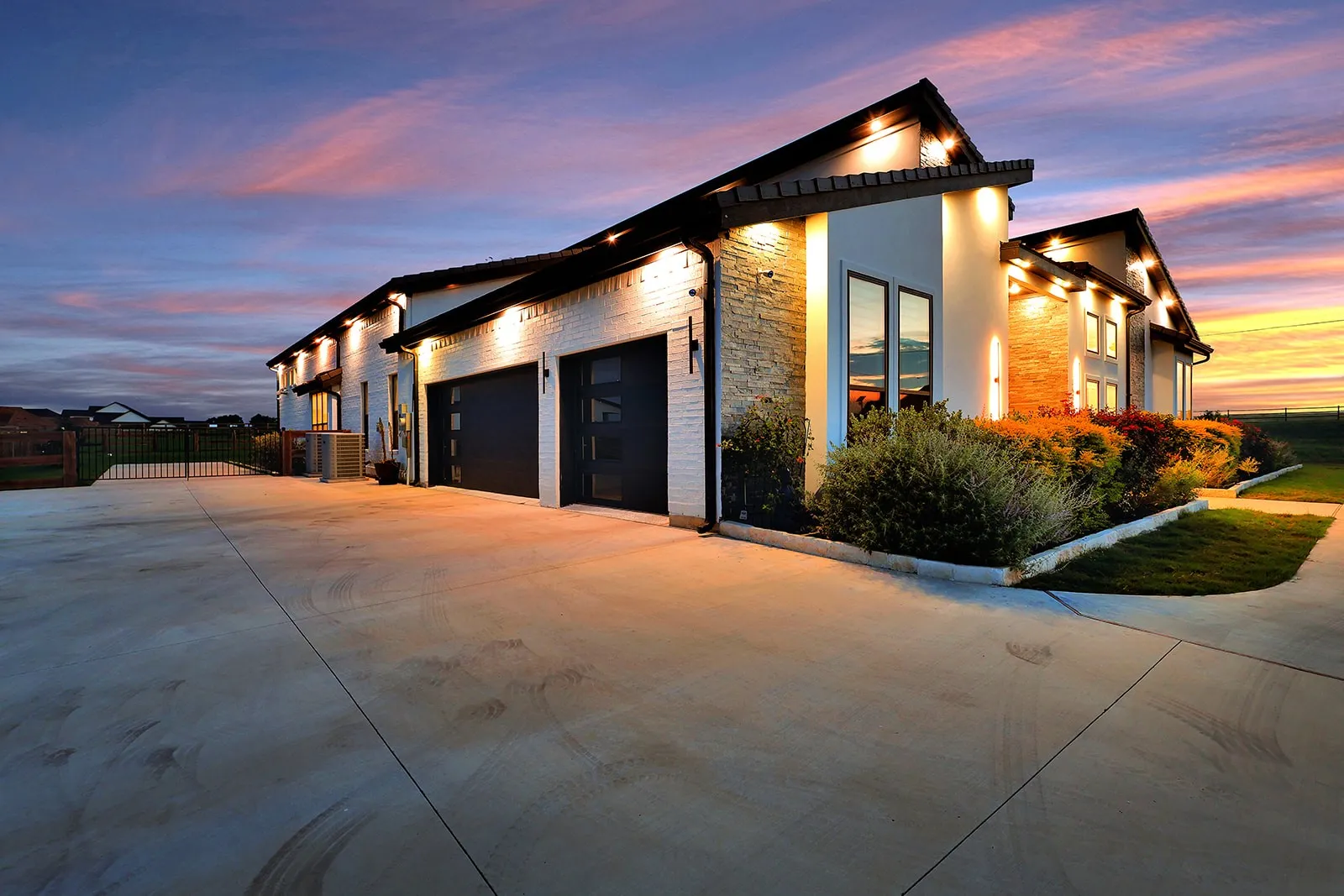 Exterior featuring a white brick and stone facade, black-framed windows, and a multi-car garage with contemporary doors