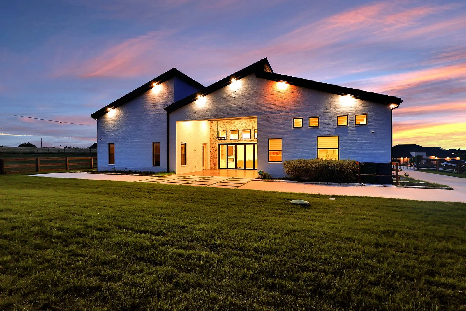 Modern architectural design with a light-colored brick exterior, a dark-pitched roofline, and ample illumination
